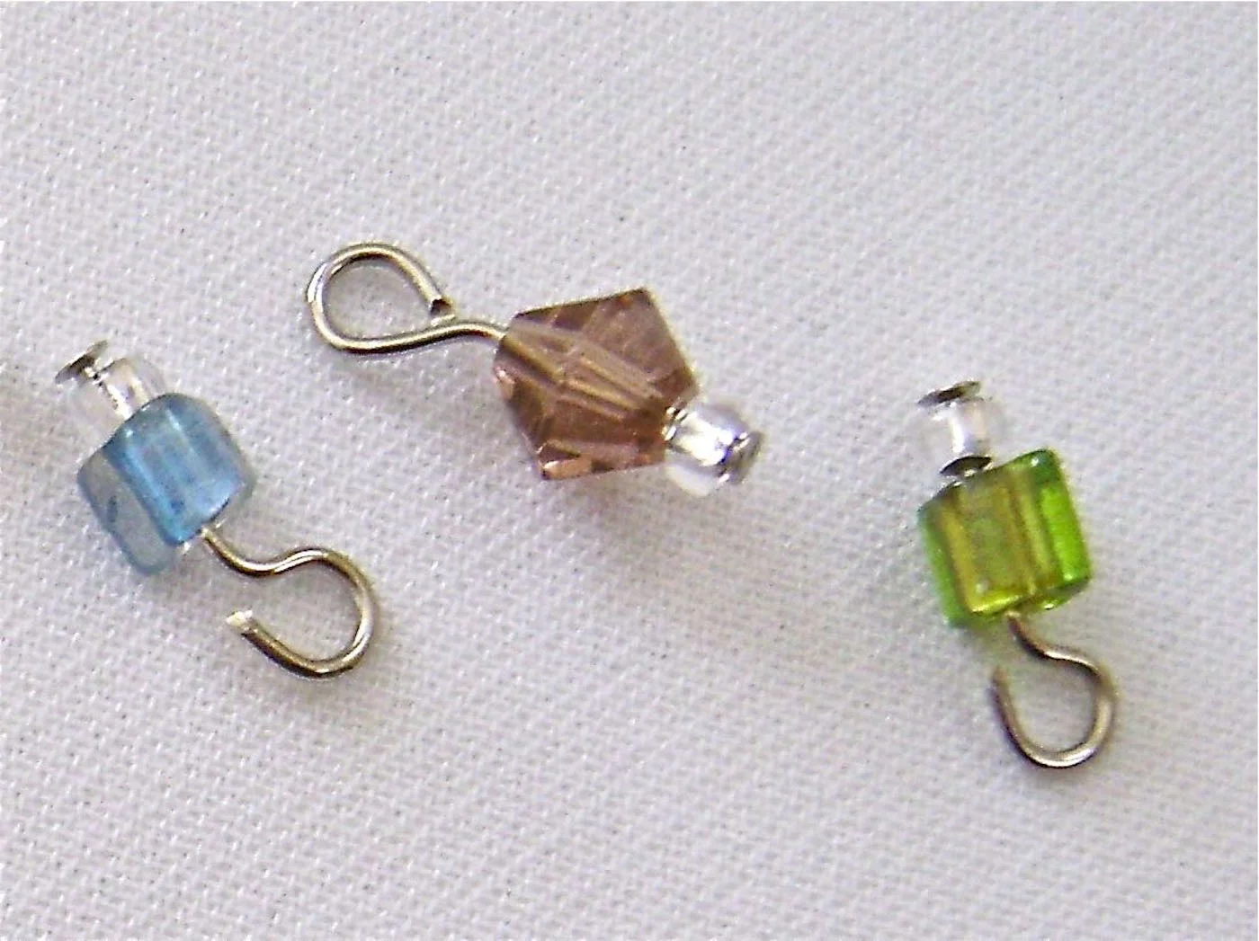 step 2 - Create a set of beads for each link in the chain. (A set = 1 blue, 1 rose, and 1 green bead). Thread a crystal seed bead and a blue cube bead onto a nail head wire. Finish by creating a loop in the wire. Do not close the loop yet. Set aside. If you’re unsure of how to make loops/eyes with wire, see the complete instructions in Jewelry Tools and Techniques .