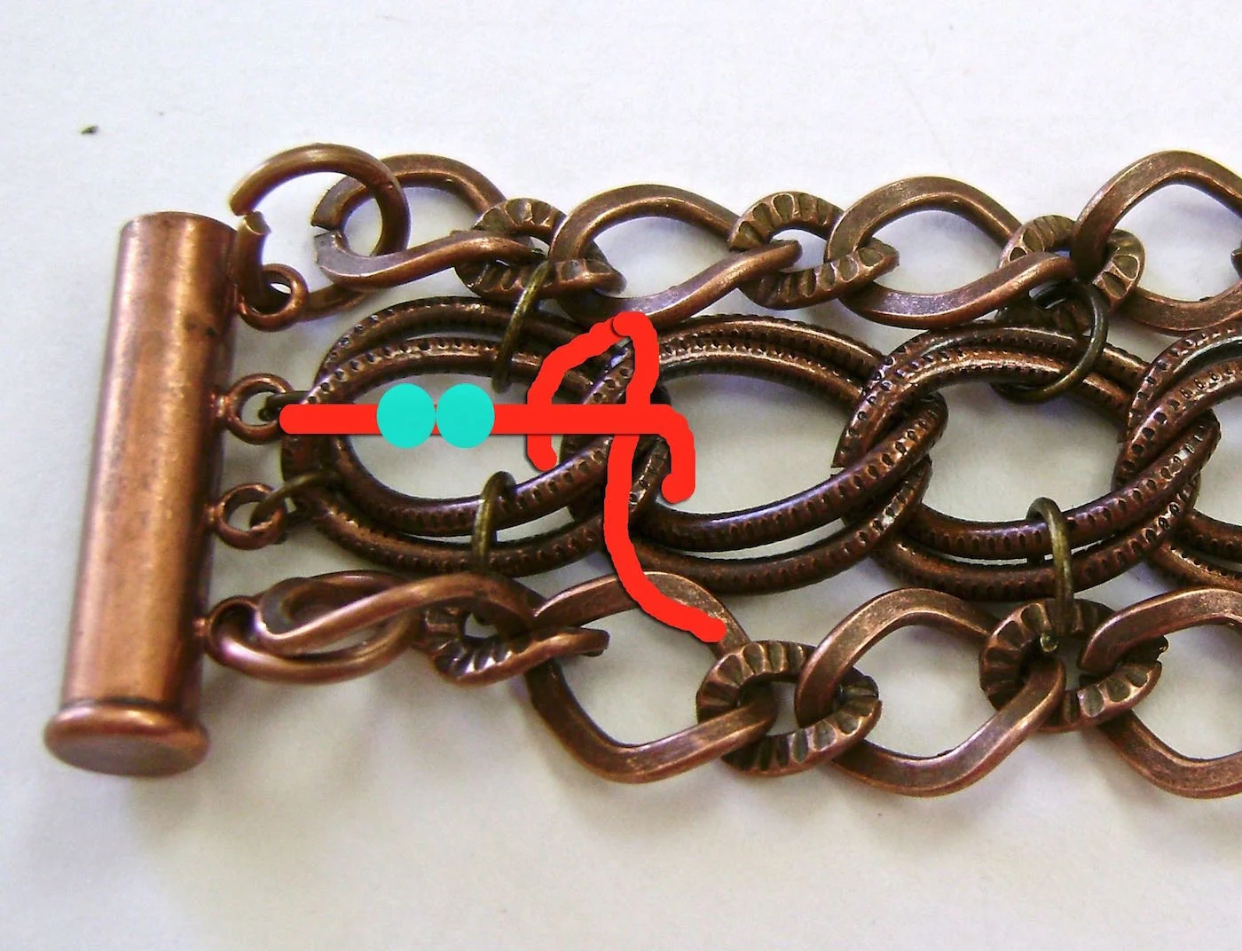 step 10 - Bring the cord under the first beaded line and pull snugly. Add two beads and repeat across the chain until beads are centered in all of the double links. Tie off the cord close to the clasp the same way you did when you began. Cut off excess cord.