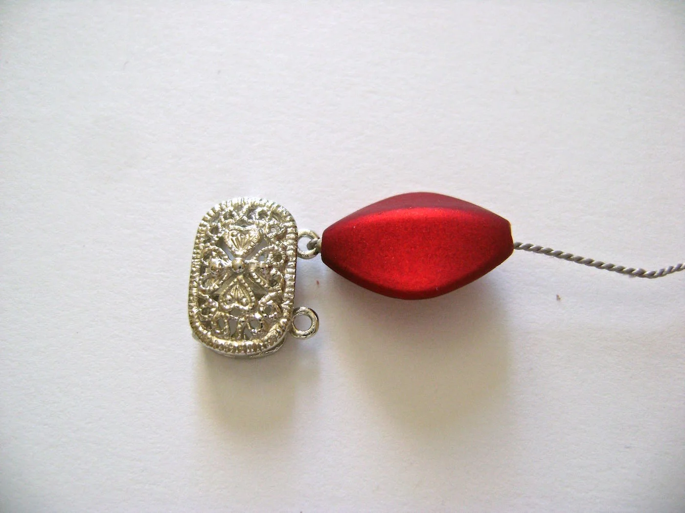 step 4 - Slip a red bead onto the cord and push it toward the clasp. The bead will cover the crimp.
