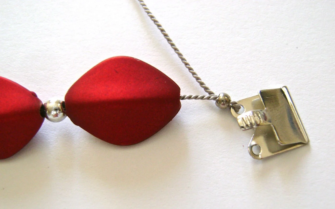 step 6 - Slide a crimp bead onto the cord. Slip the cord through the loop in the clasp, then back through the crimp bead. Pull the cord snugly to eliminate spaces between the elements on the cord. Crimp the bead and cut off the cord’s short tail.