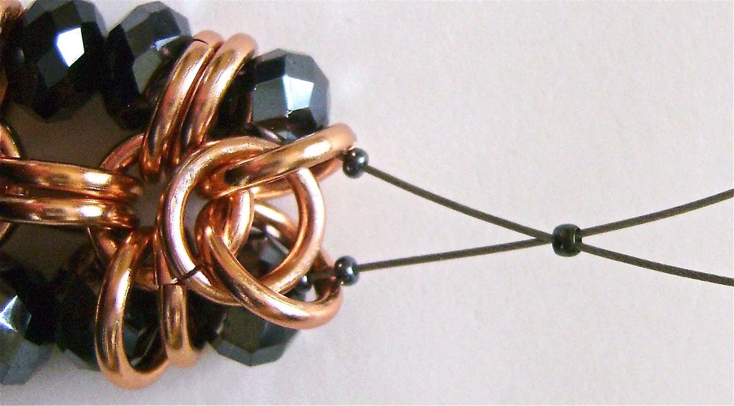 step 8 - Pass the wire through a single bead. Add two seed beads to each wire. Put both wire ends into a crimp bead and pull them snugly Be sure to pick up any slack. Crimp the bead to secure the wire. Trim the excess. The crimp will be hidden inside the copper rings.