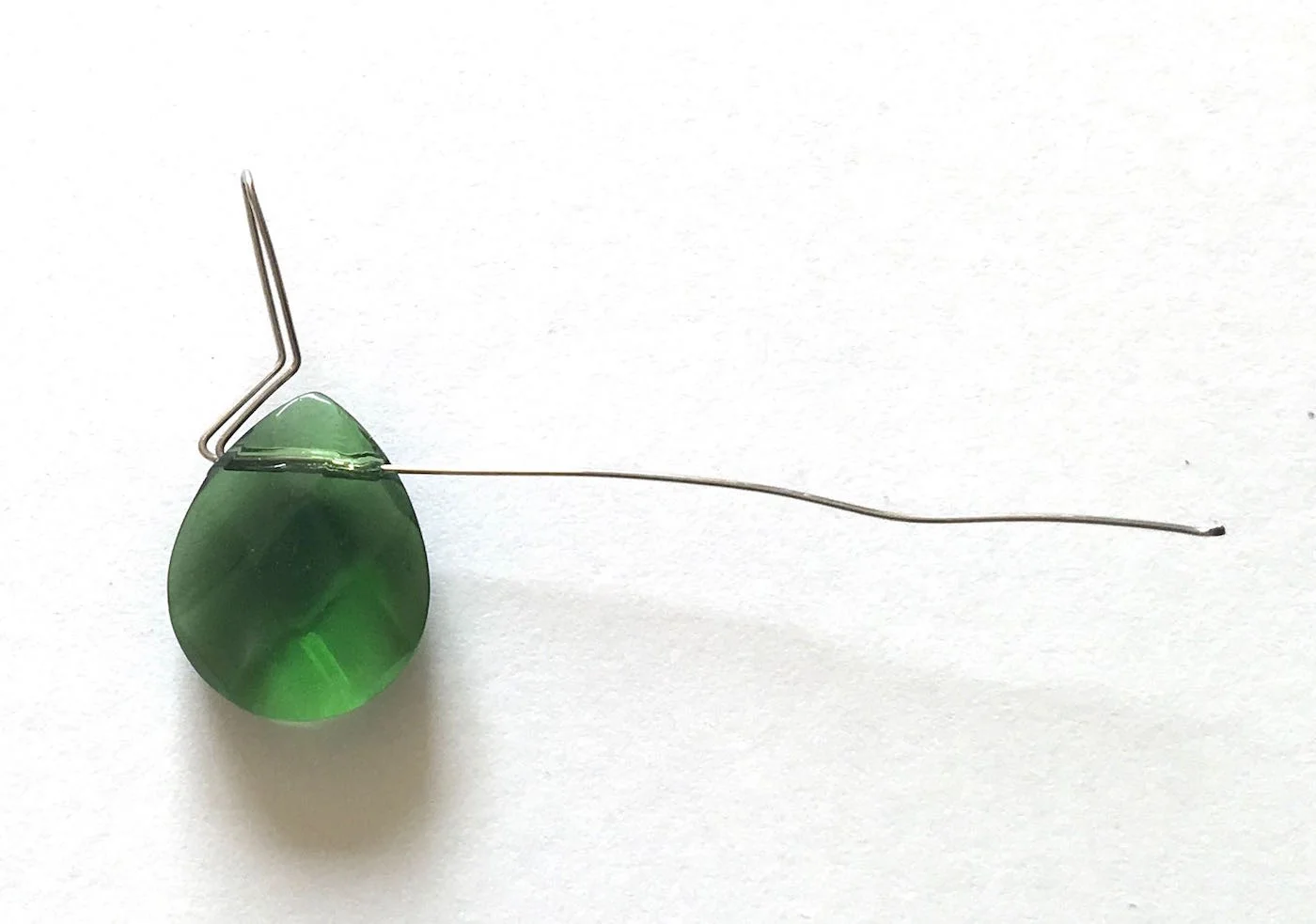 step 7 - Press the looped wire against the side of the bead. Use flat nose pliers to create a slight bend away from the bead in the looped wire.