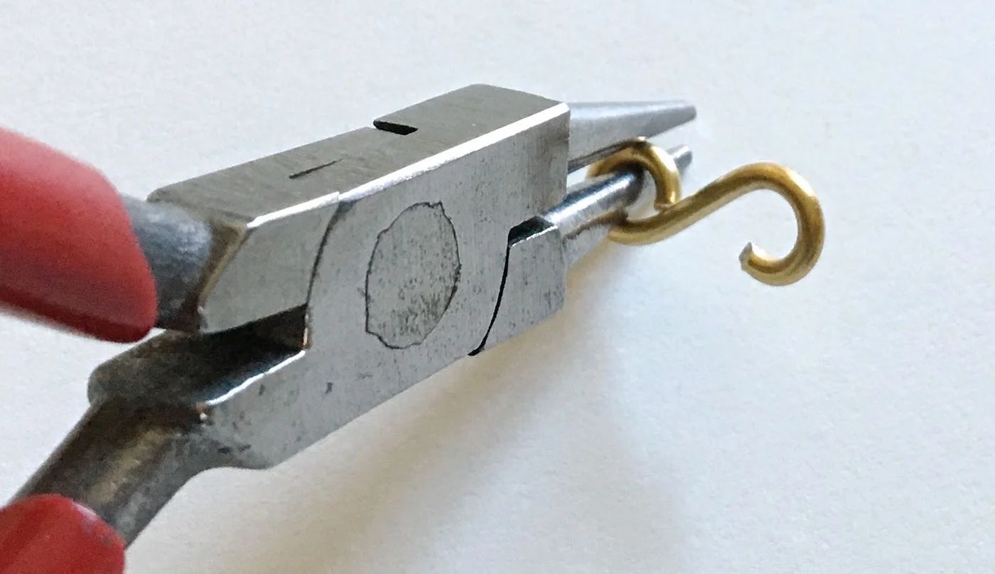 step 9 - Use the round nose pliers to close the curls again. Keep adjusting as necessary until the figure eight fits between the bracelet frame.