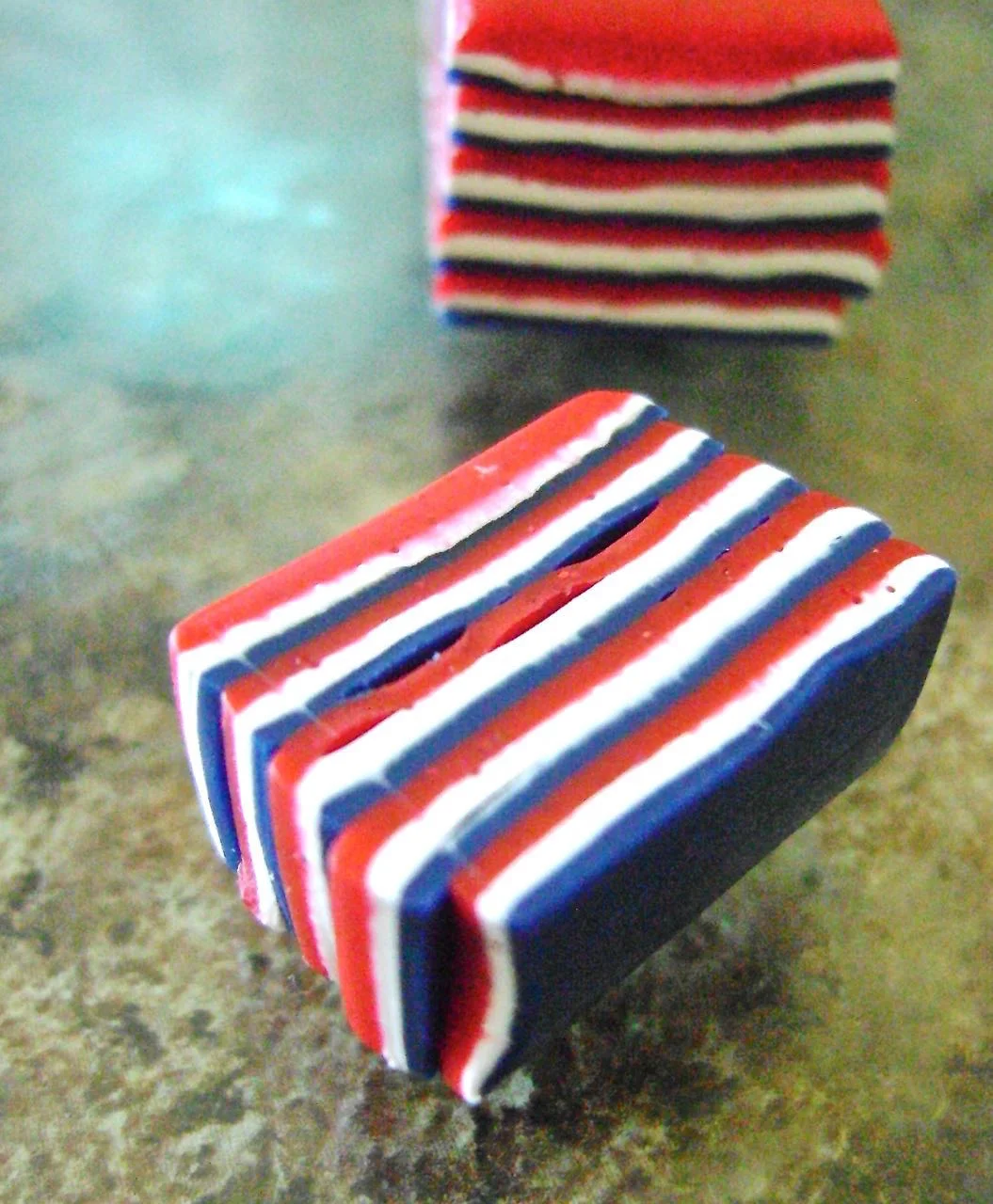 step 2 - Lay the pieces on the work surface with the blue first, then the red, then the white. Slice vertically through the pieces creating thin one inch rectangles. Stack them on top of each other until you have 9 or more pieces stacked.
