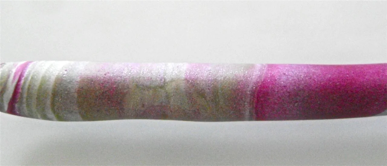 step 2 - Cut through the stack from top to bottom cutting .50” wide slices. Roll each slice into a cigar shape on the work surface. Now twist and roll again to blend the colors. If you’re not happy with the result, fold the “cigar” in half and roll again until you have the color blend and thickness you want for the bead. Steps and photosare included here for oval beads because I was going to use them but changed my mind. If you want the same shape beds as my necklace skip steps 3-5. The oval beads should be about 5/8” thick.