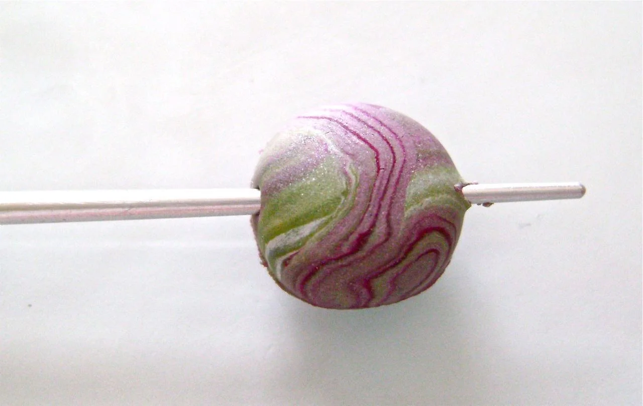 step 8 - Create holes in the beads by first lightly piercing one side with the narrow end of an Etch ‘N Pearl tool. Remove the tool and bring it to the other side and with a gentle turning motion, move the tool through the bead and out the pierced end.