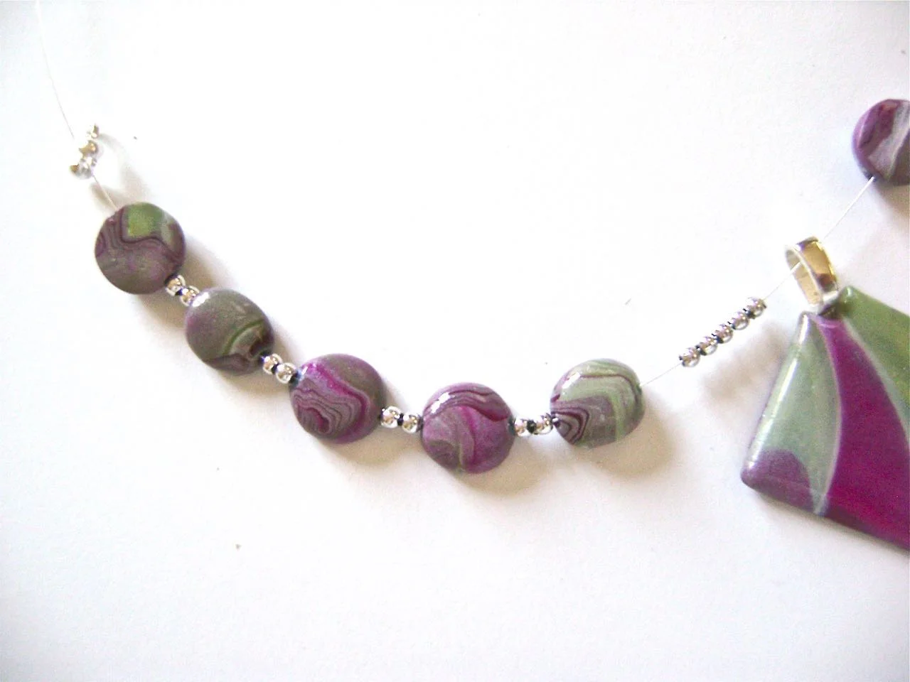 step 13 - Add 5 clay beads onto a strand of beading wire with two silver beads separating each. After the fifth bead add 5 silver beads followed by the pendant. Add 5 more sets of clay and silver beads.