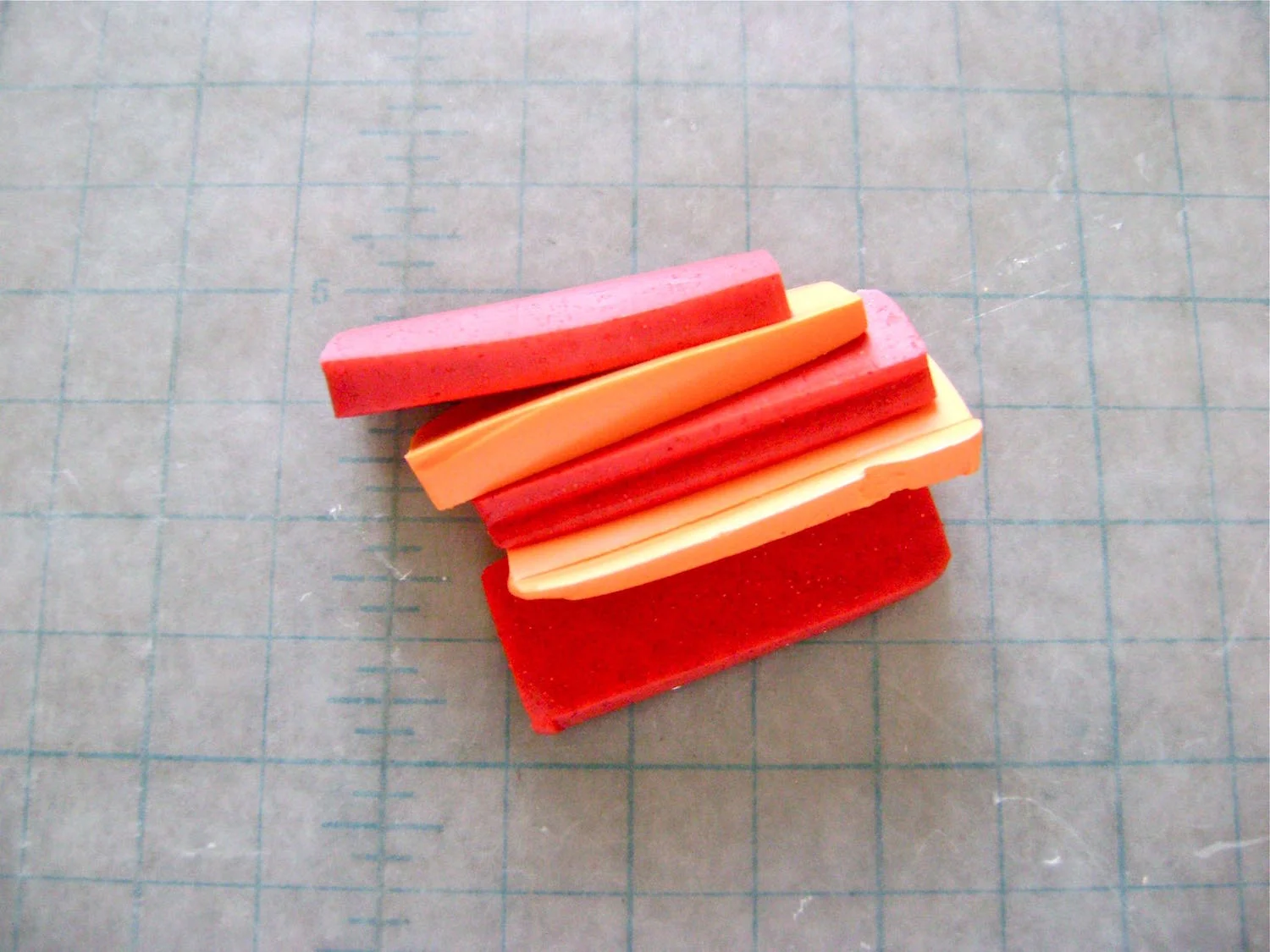 step 1 - Cut the orange and pink clay into thin slices and condition. Blend them together with a roller or pasta machine to create the watermelon color. Cut the clay into a 1.25” x 7” strip, or the size that will fit your round cookie cutter. Wrap heavy-duty foil around the cutter followed by the clay strip. Adjust the size if necessary. Blend the ends together to create a ring.