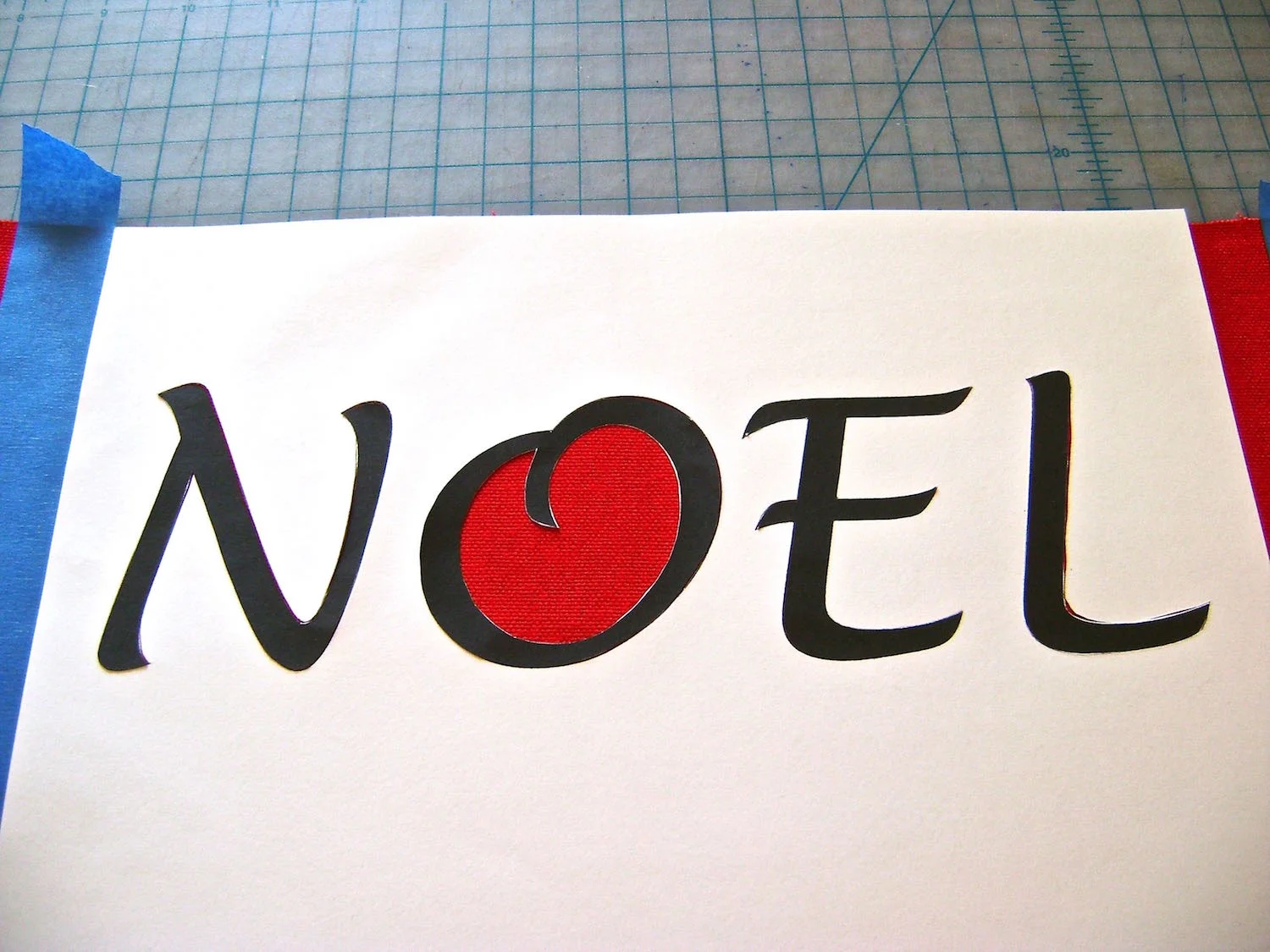 step 7 - Place the four die-cut letters into position on the Noel stencil. Press down all the edges until they securely adhere to the fabric.