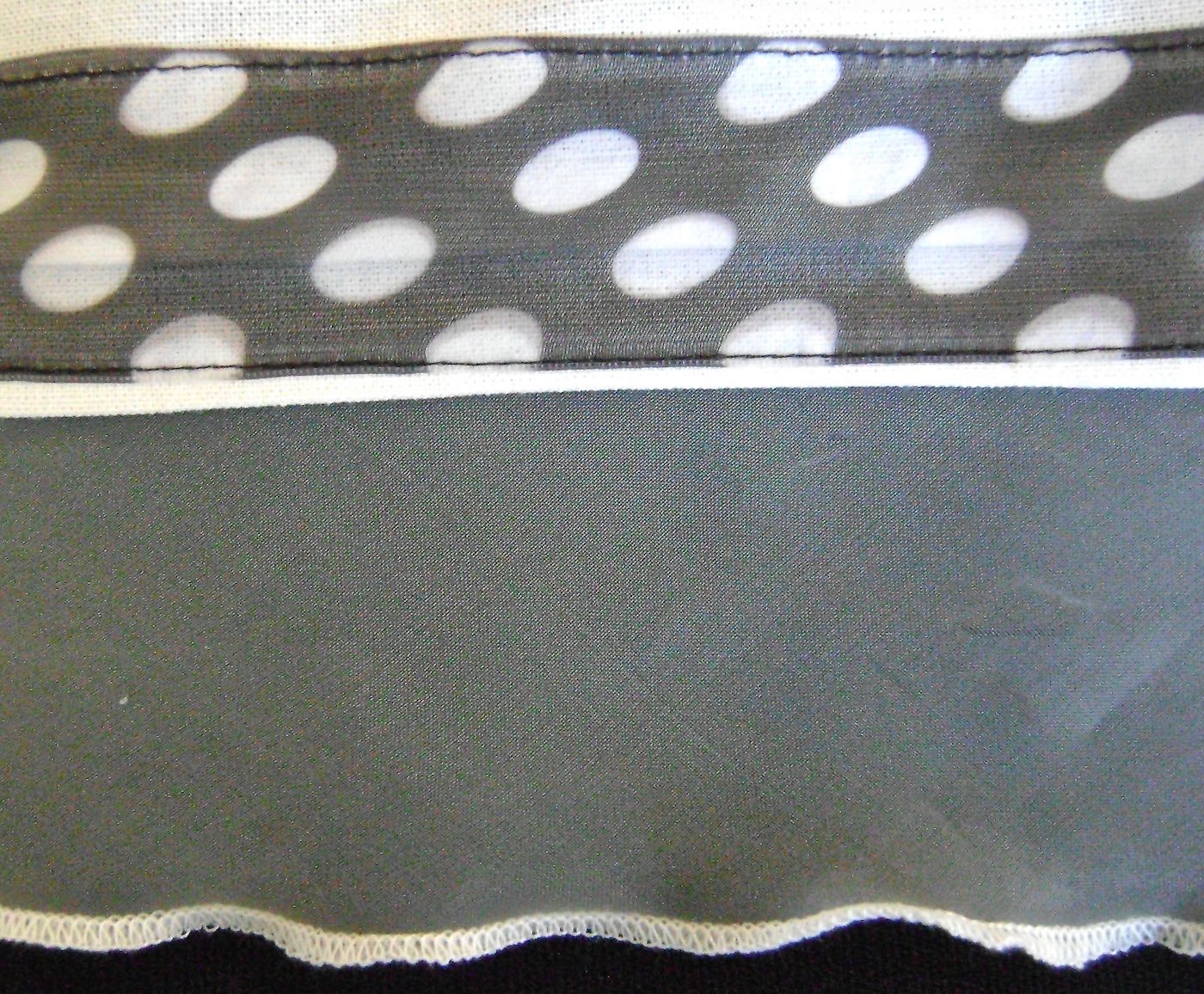 step 8 - Align the ribbon to the seam where the sheer and the cotton fabrics meet and pin in place. Stitch across both ribbon edges. step 9 - Using a rolled hem on the serger machine, stitch across the raw edge of the sheer ruffle. If you don’t have a serger you can use a close zig zag stitch or some other decorative stitch. step 10 - Continue making the apron per the pattern instructions.