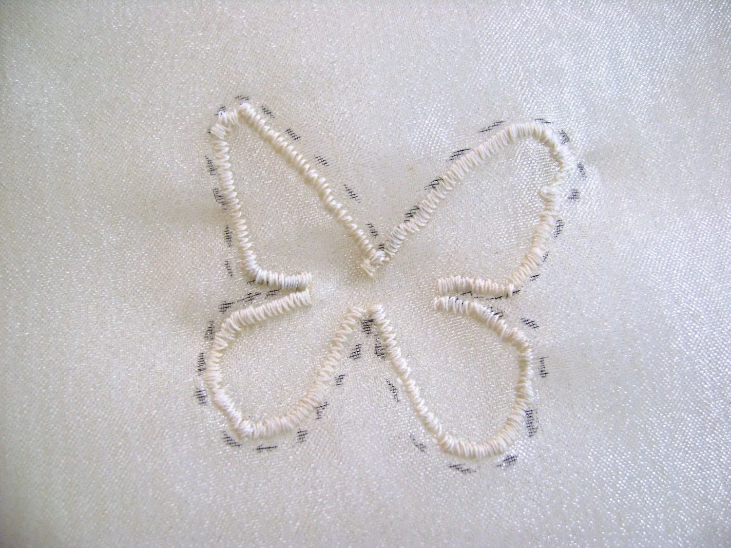 step 16 - Using a satin stitch presser foot and a tight zigzag stitch, sew inside the dots you’ve marked on the fabric. Lift the presser foot and turn the fabric to smoothly navigate angles and tight curves.