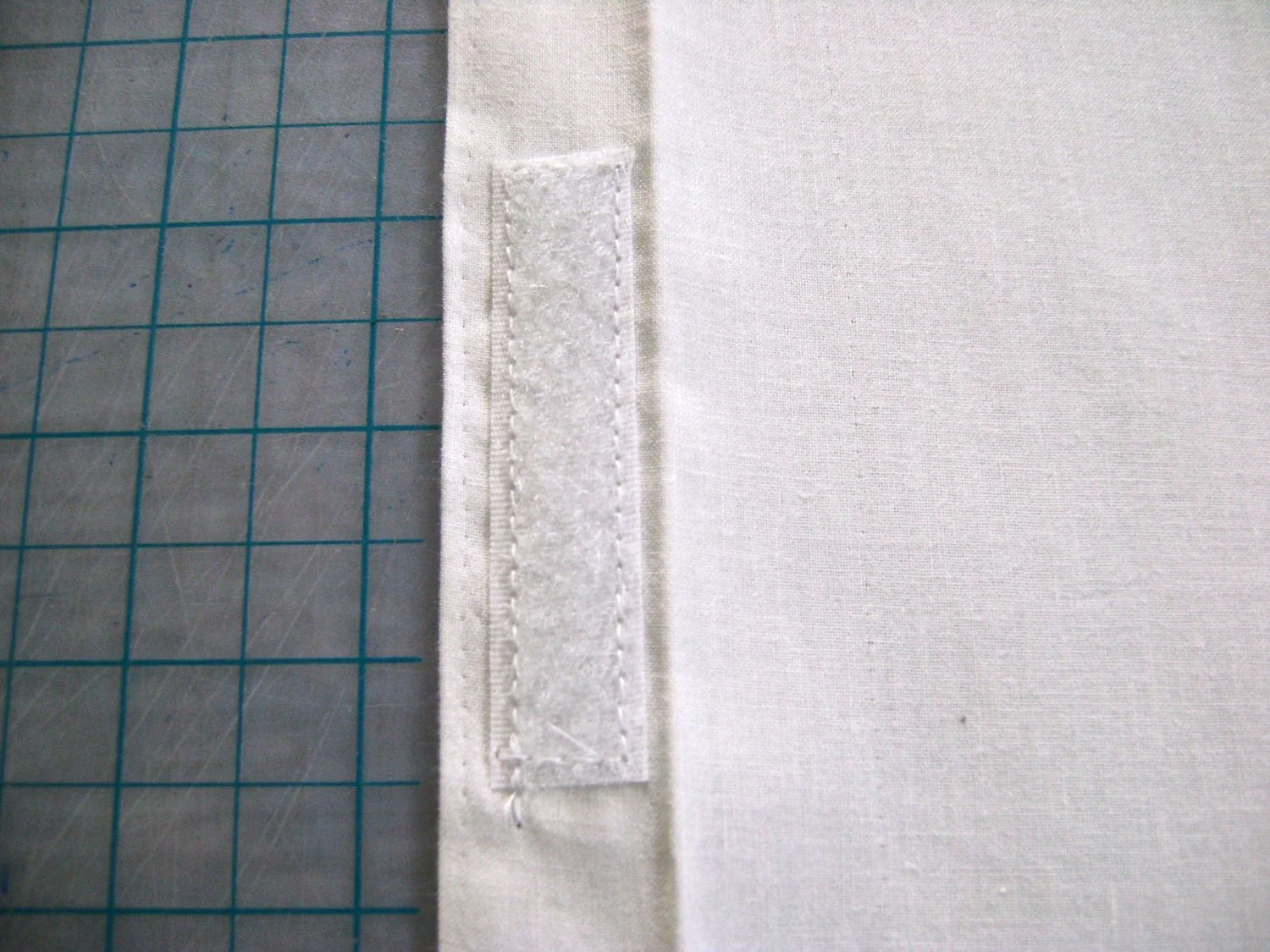 step 22 - On one piece, sew one half of a 3” Velcro strip to the center of the hem. Fold the 1” hem over again and sew close to the edge the entire length of the fabric. The piece should now measure 7.75” x 13.25.