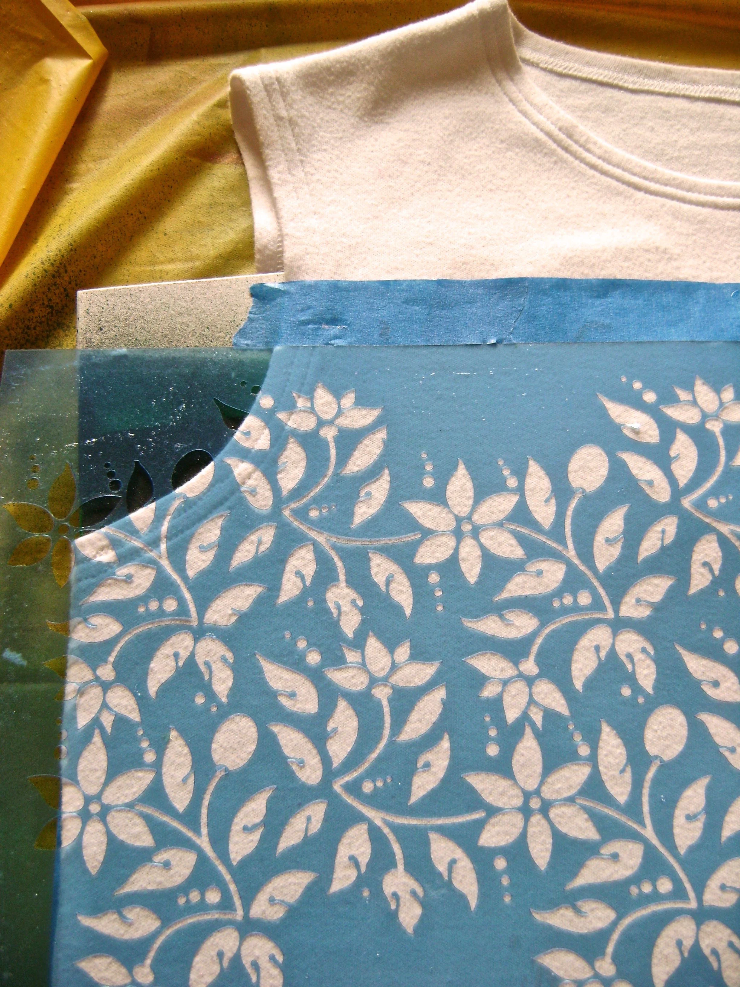 step 4 - Place the stencil on the left side of the shirt with the top edge up against the bottom of the painters tape, and the right edge of the design aligned with the shirt center. Do not align the right edge of the stencil sheet with the shirt center. Press down to adhere the stencil to the shirt. Step 5 - Spray paint the design.