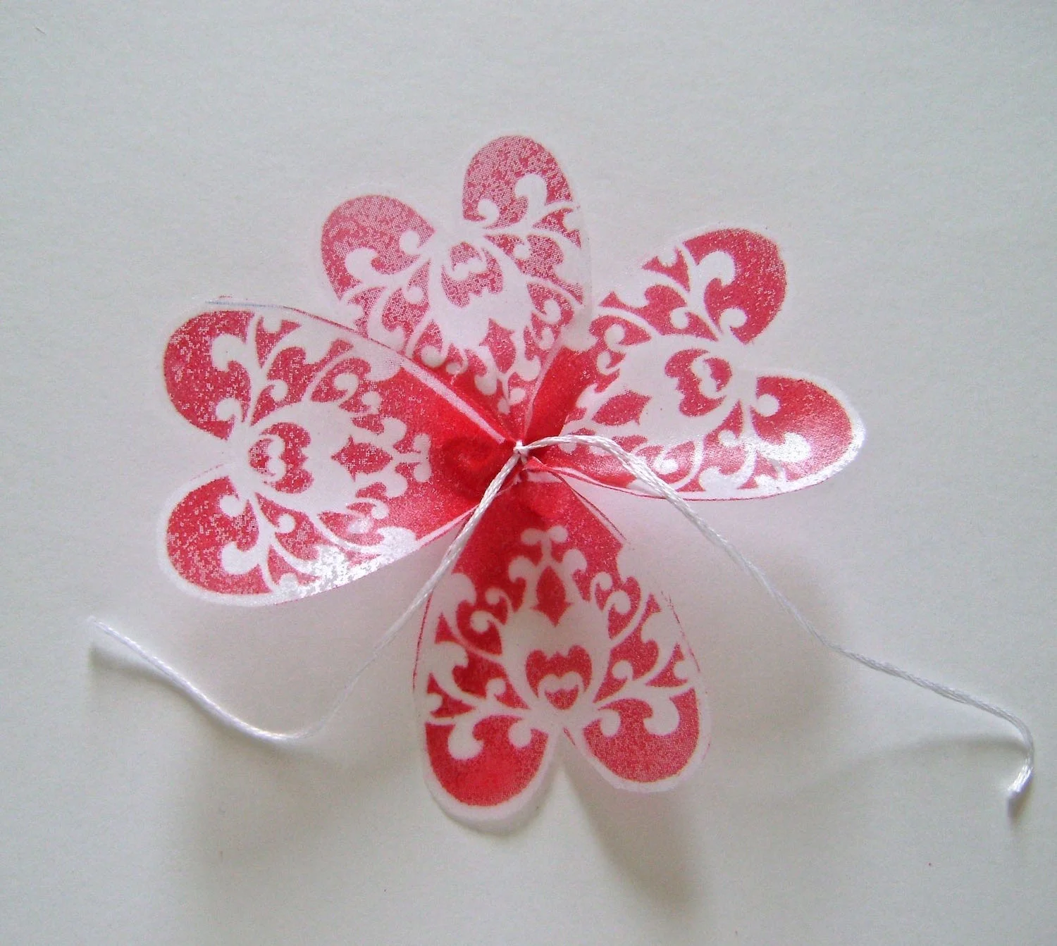 step 9 - To assemble the flower, stack the petals with the largest on the bottom and the smallest on top. Stack each section in a different direction than the one below it. Each time you add another section, tie the string tails under the section below it. Knot the string and cut off the tails. 