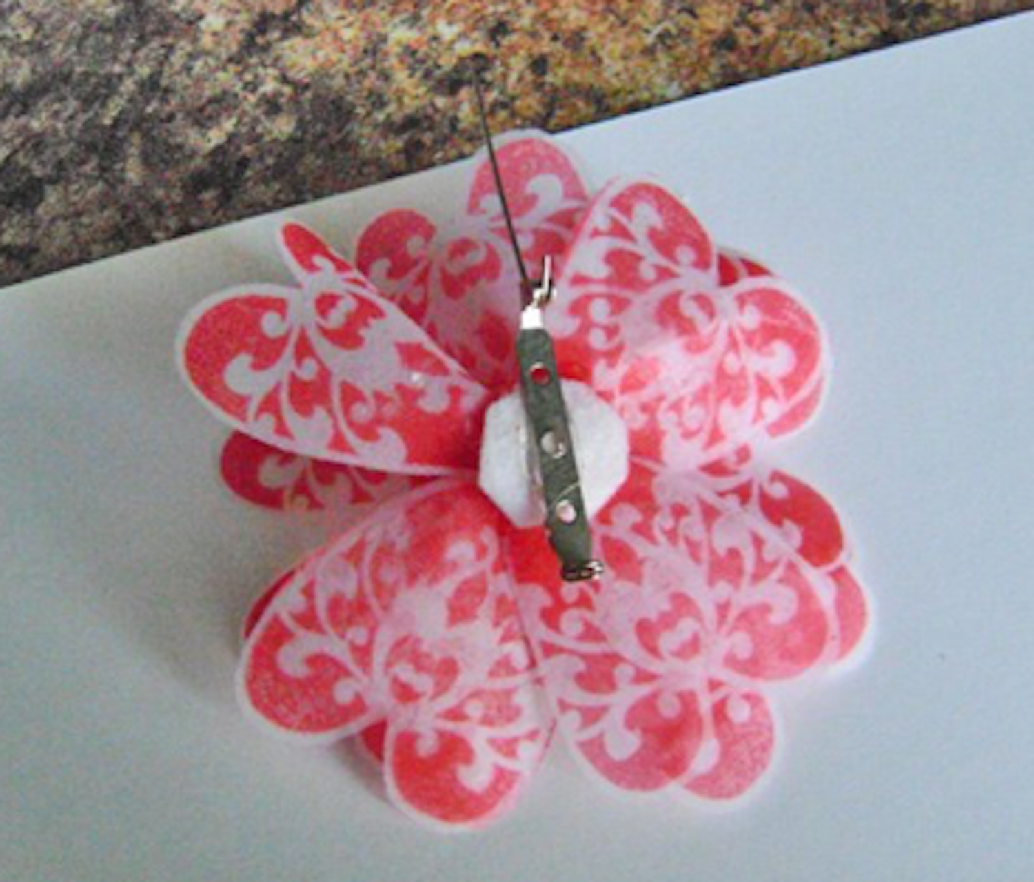 step 10 - Turn the flower bottom side up and glue a small circle of felt or fleece over the knot with Fabri-Tac. Use Dazzle-Tac or other jewelry glue to attach a pin.