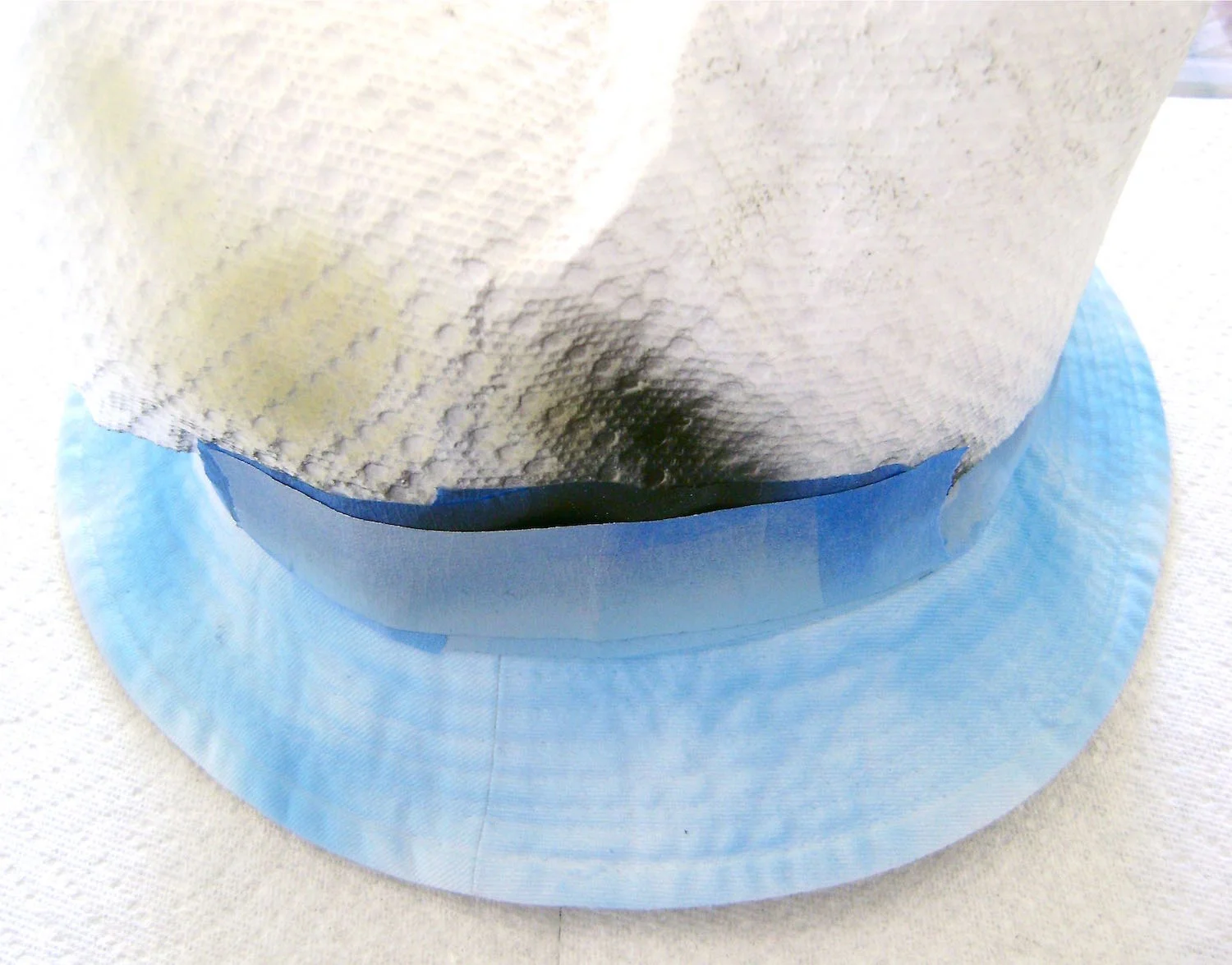 step 6 - Spray the inside brim of the hat in random patterns with first the light, then medium, and then dark blue. Use the dark blue sparingly and leave some of the white of the brim showing. 