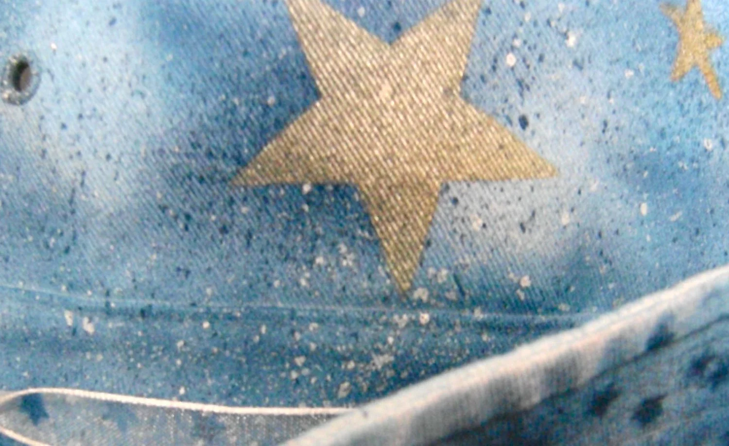 step 12 - Splatter patterns are created using a toothbrush dipped alternately in white and dark blue paint. Tap the paint-dipped toothbrush on the container to remove excess paint and avoid big splotches on the hat. With a gloved finger, flick the bristles of the toothbrush near the hat’s surface to create tiny splatters. 