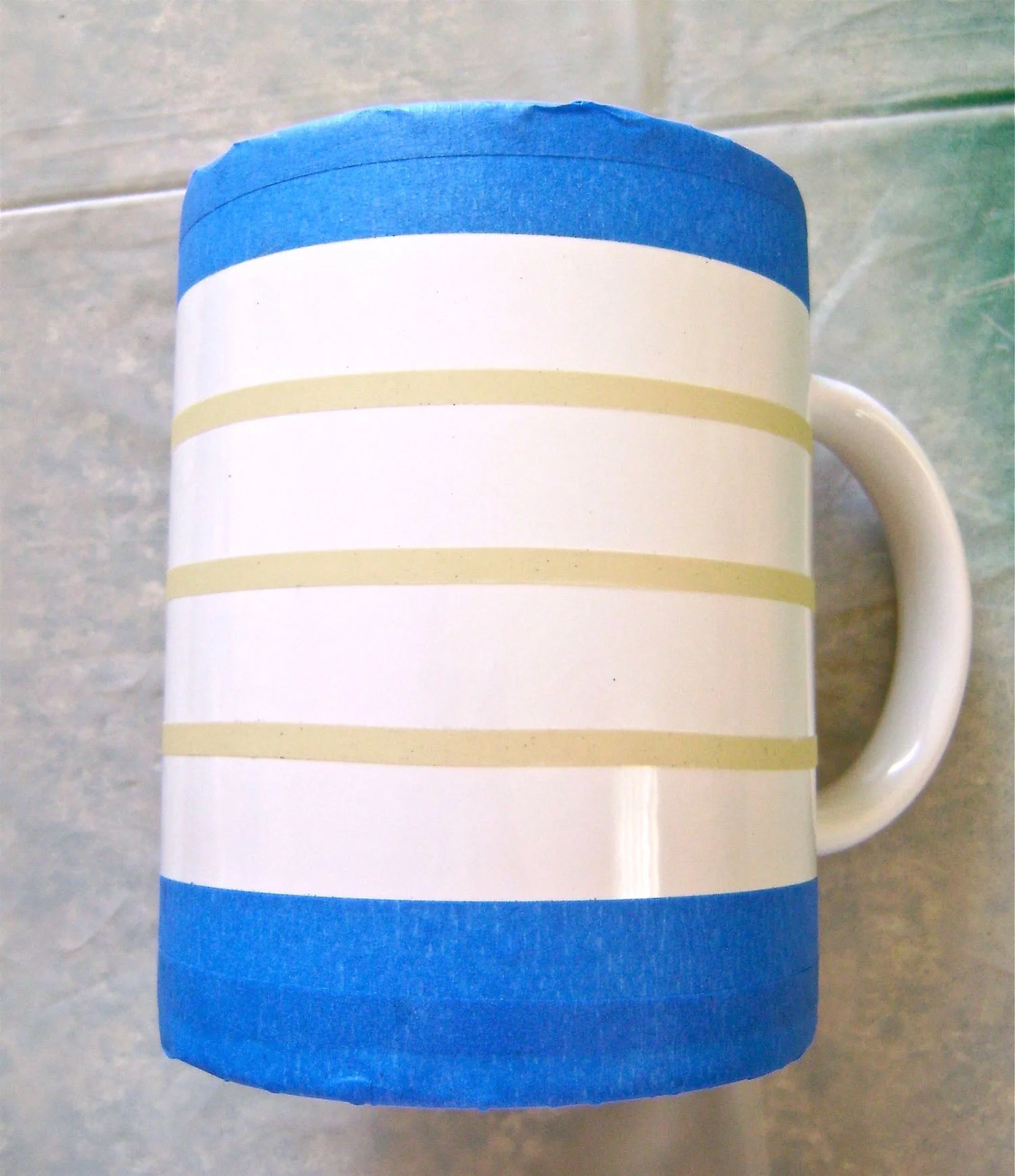 step 4 -Measuring 1” from the edge of the top masking tape, place ¼” tape around the mug, stopping at the vertical tapeline. Place two more lines around the mug positioned 1” apart.