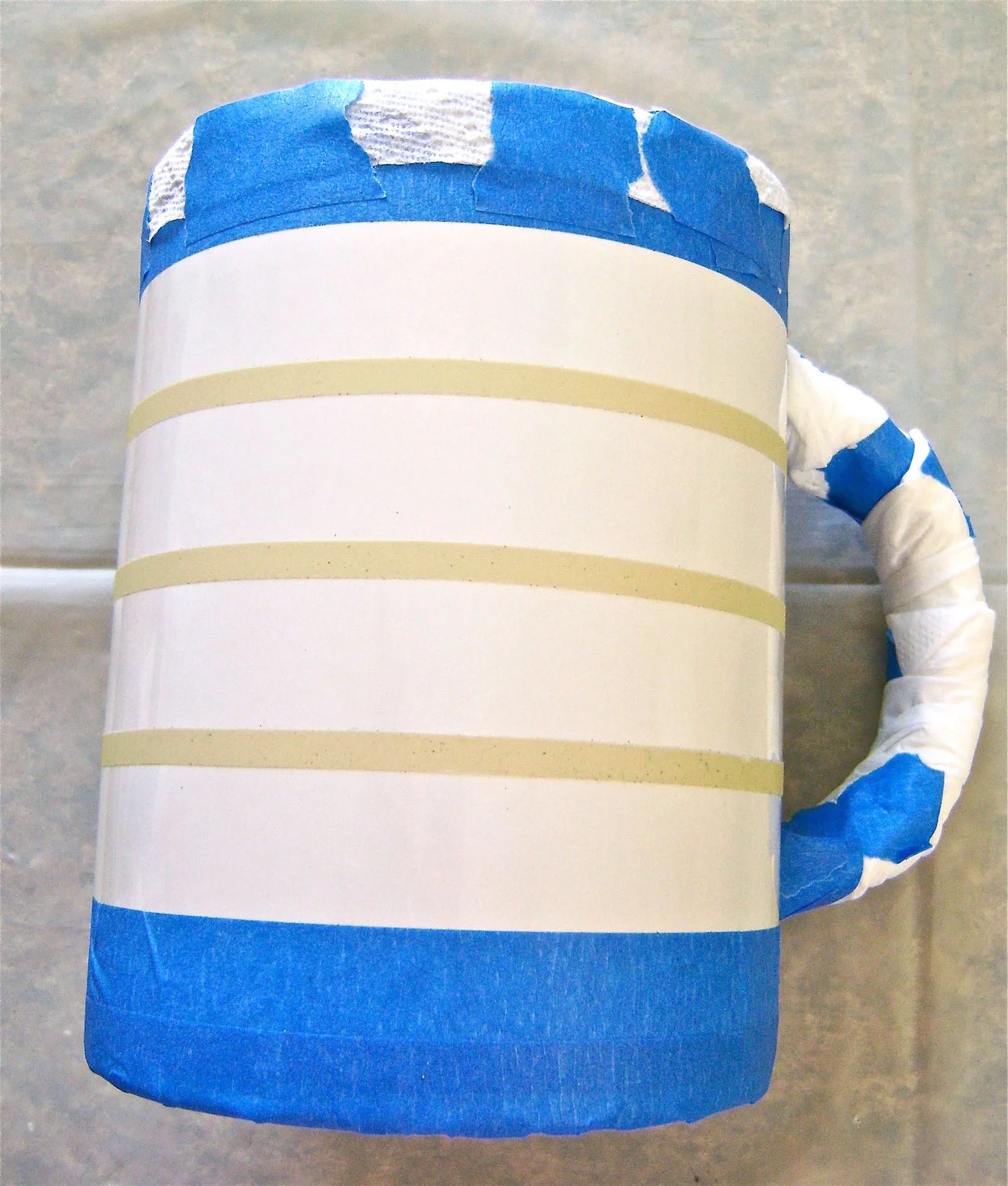 step 5 - Mask the inside of the mug with a paper towel. Tape the edge of it to the top edge of the mug. Wrap tissue around the mug handle.