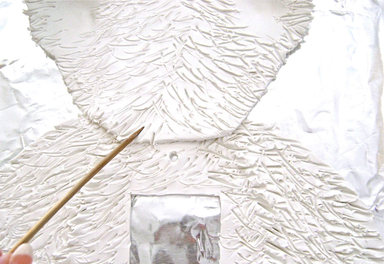 step 13 - Go over the areas of the head that overlap the body and arms, jabbing with the wood pick. Apply more pressure, which will join the pieces together.
