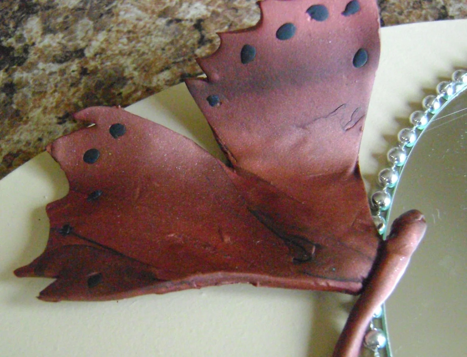 step 14 - Glue the butterfly wings to the plaque using Dazzle-Tac. Allow the butterfly to overlap the mirror slightly.