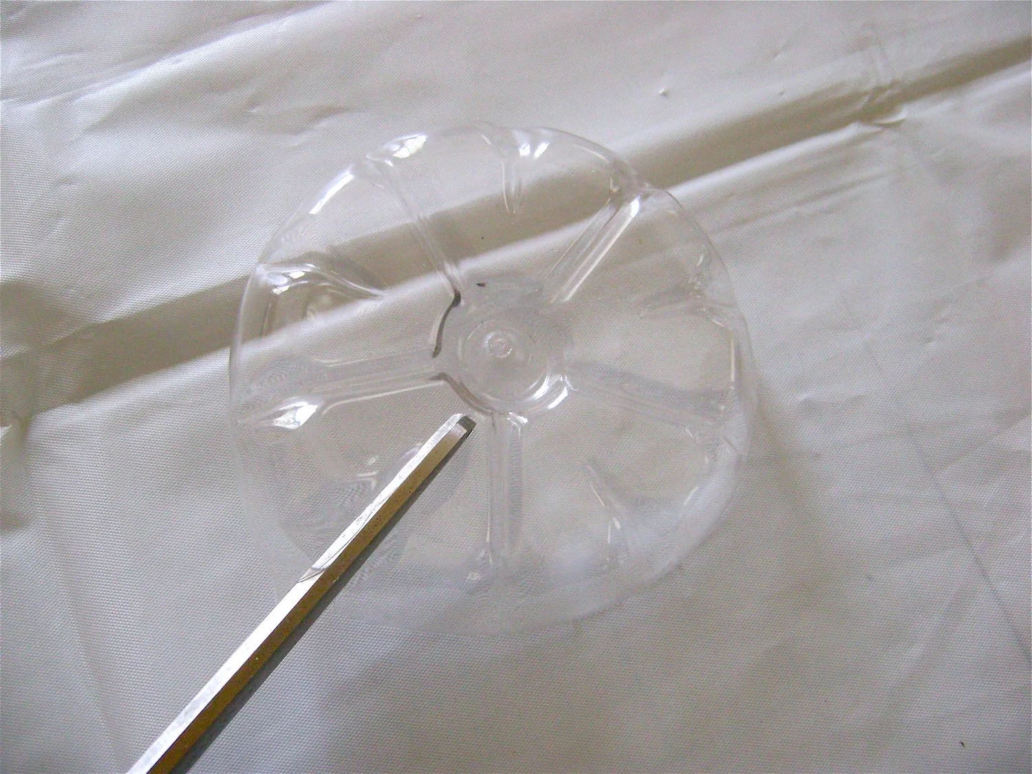 step 2 - Cut across the grooves to the center circle imprinted in the plastic. Shape the squared edges if you like by curving them into rounded petal shapes.
