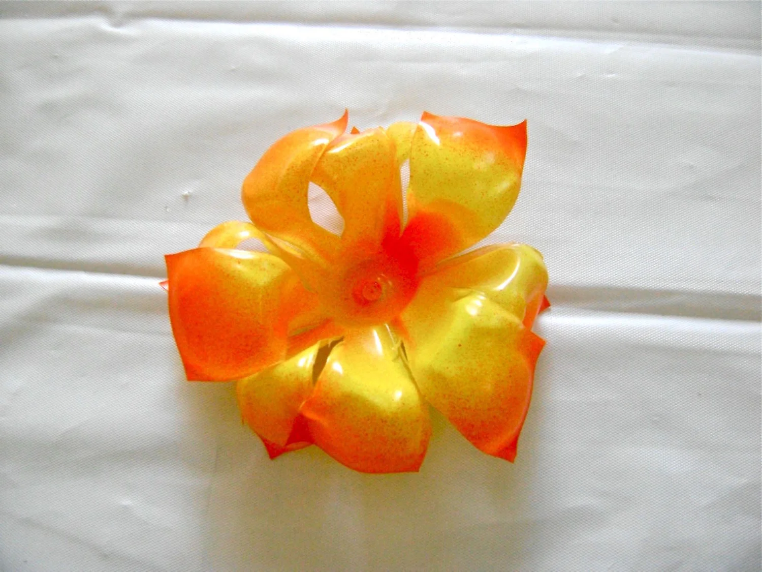 step 5 - A hot blow dryer will also shape the plastic to some extent but it takes longer and the results will be less dramatic. The heat gun causes the petals to curl under as in the photo above. If you don’t have a heat gun, a candle flame might work too.