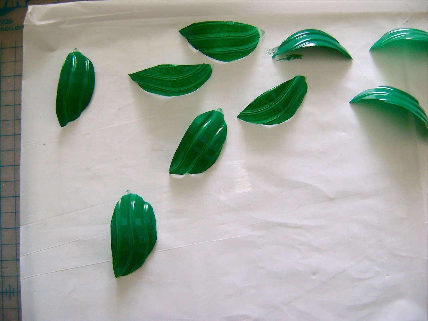 step 6 - Cut 2” - 3” leaf shapes out of the remaining plastic bottle - two for each flower. Airbrush them with green paint.