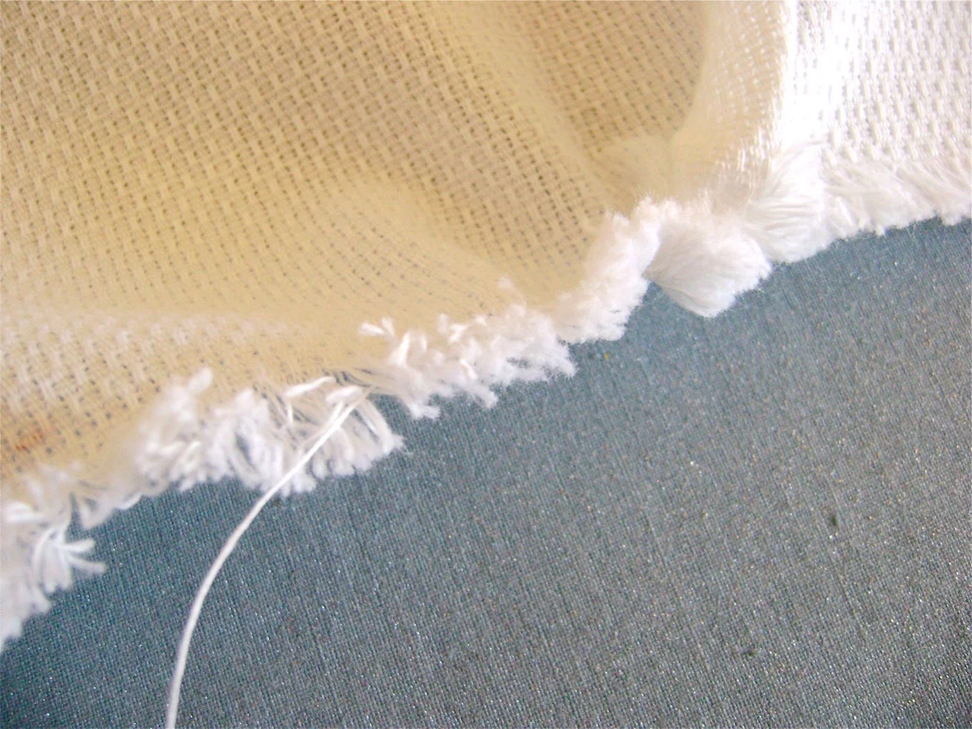 step 3 - If you have a problem pulling a thread, it’s usually because another thread is blocking it somewhere along the width. Use the pin to find it, pulling at threads along the edge. 