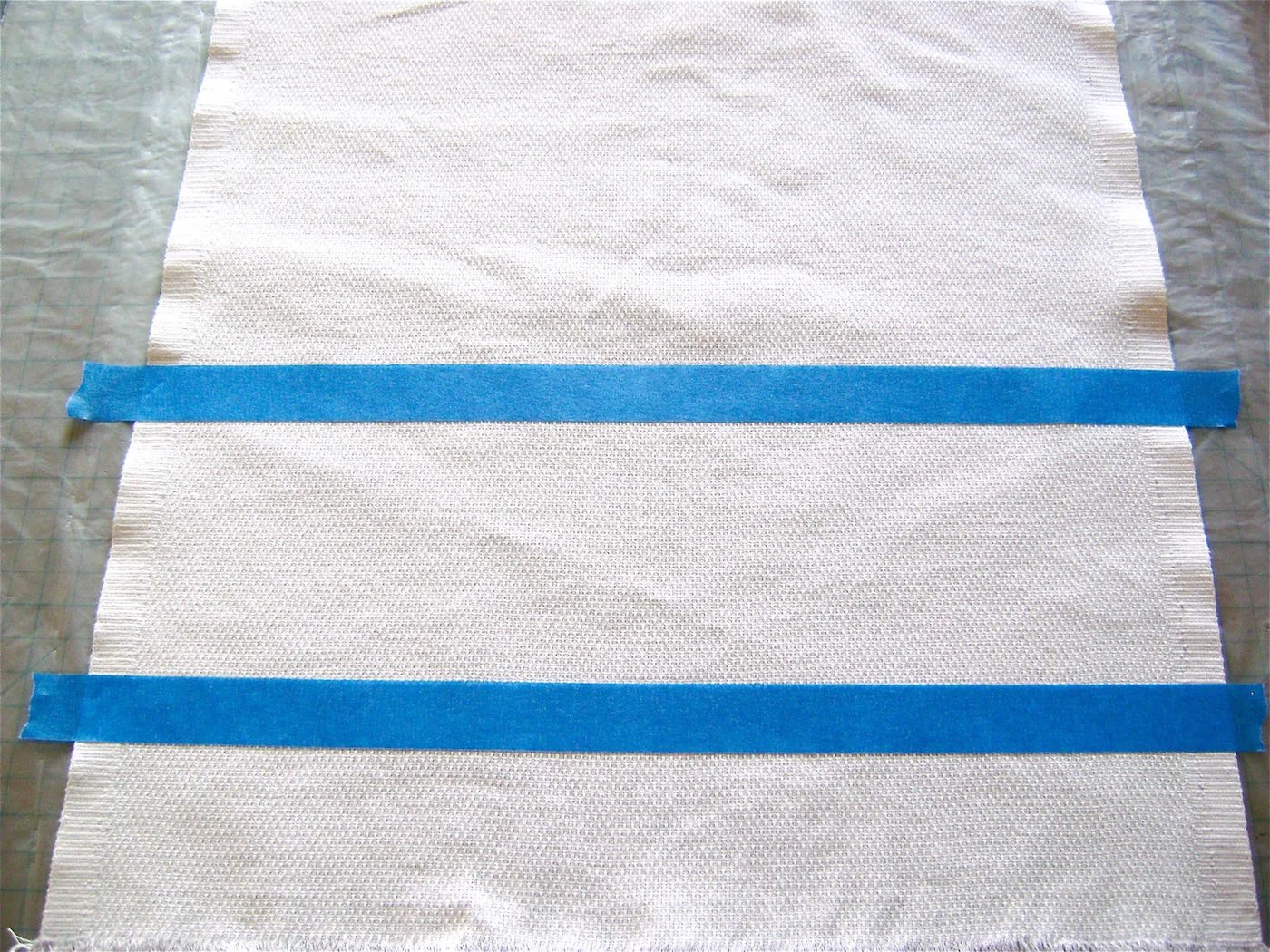 step 8 - Place painters tape eight inches from both fringed edges of the Hucktowel. Place another strip of tape four inches away from the first creating the four- inch border to be painted.