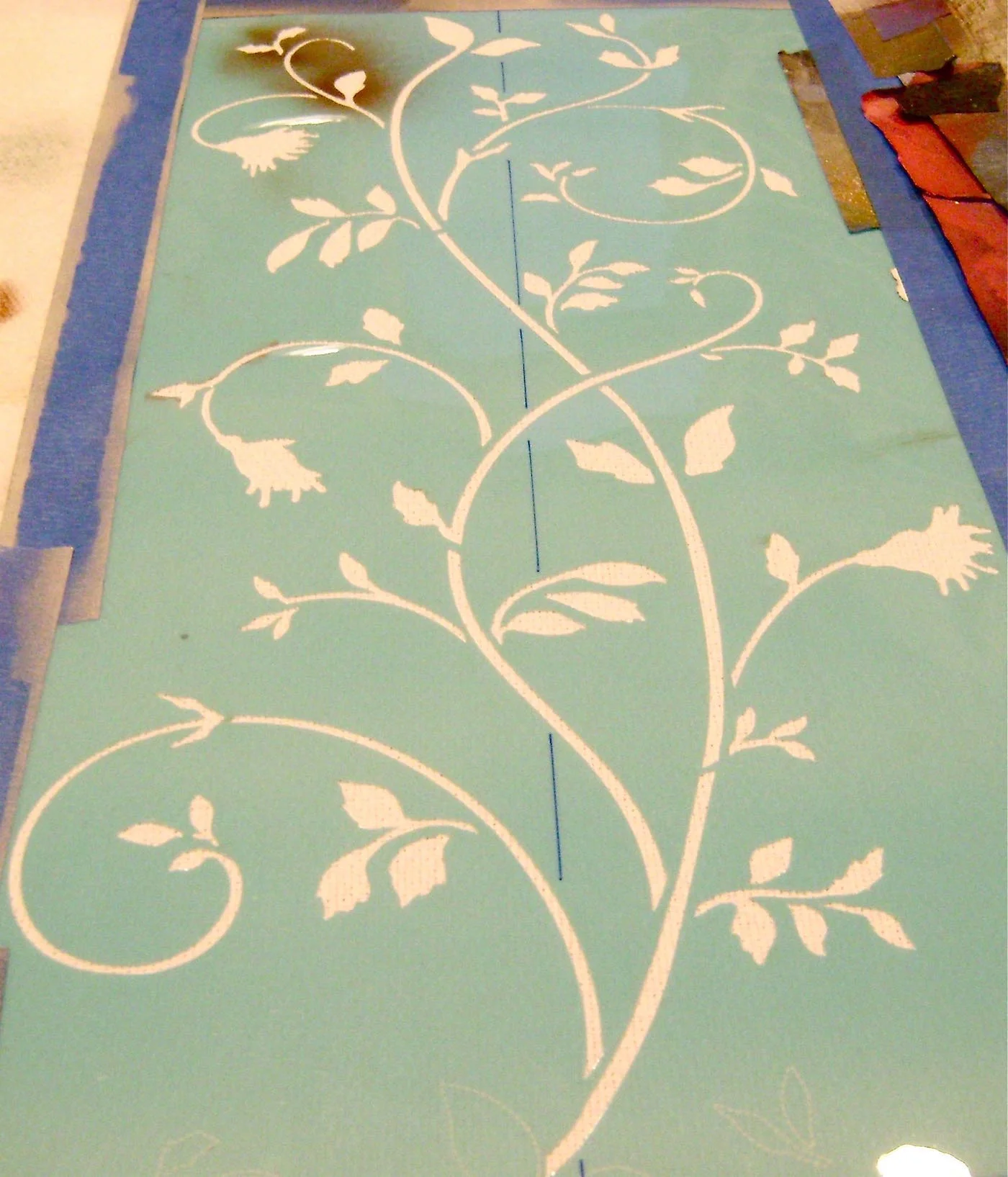 step 12 - Spray adhesive on the 15” stencil. Place it on the runner with the leafy edge 1 ½” from the border, matching the line on the stencil with the center of the runner. Paint the large stencil the same way you did the border stencil, applying olive color then adding details with sienna paint. Remove the stencil and repeat on the other end of the runner.