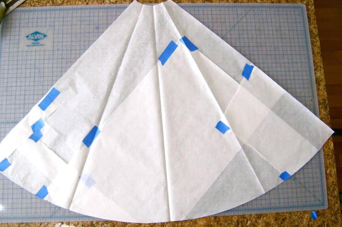 step 7 - Connect the dots creating the cutting line for the pattern bottom. Cut on the curved line. Unfold the pattern piece. This represents a quarter of the tree skirt. Use this pattern to cut out four identical pieces of fleece.