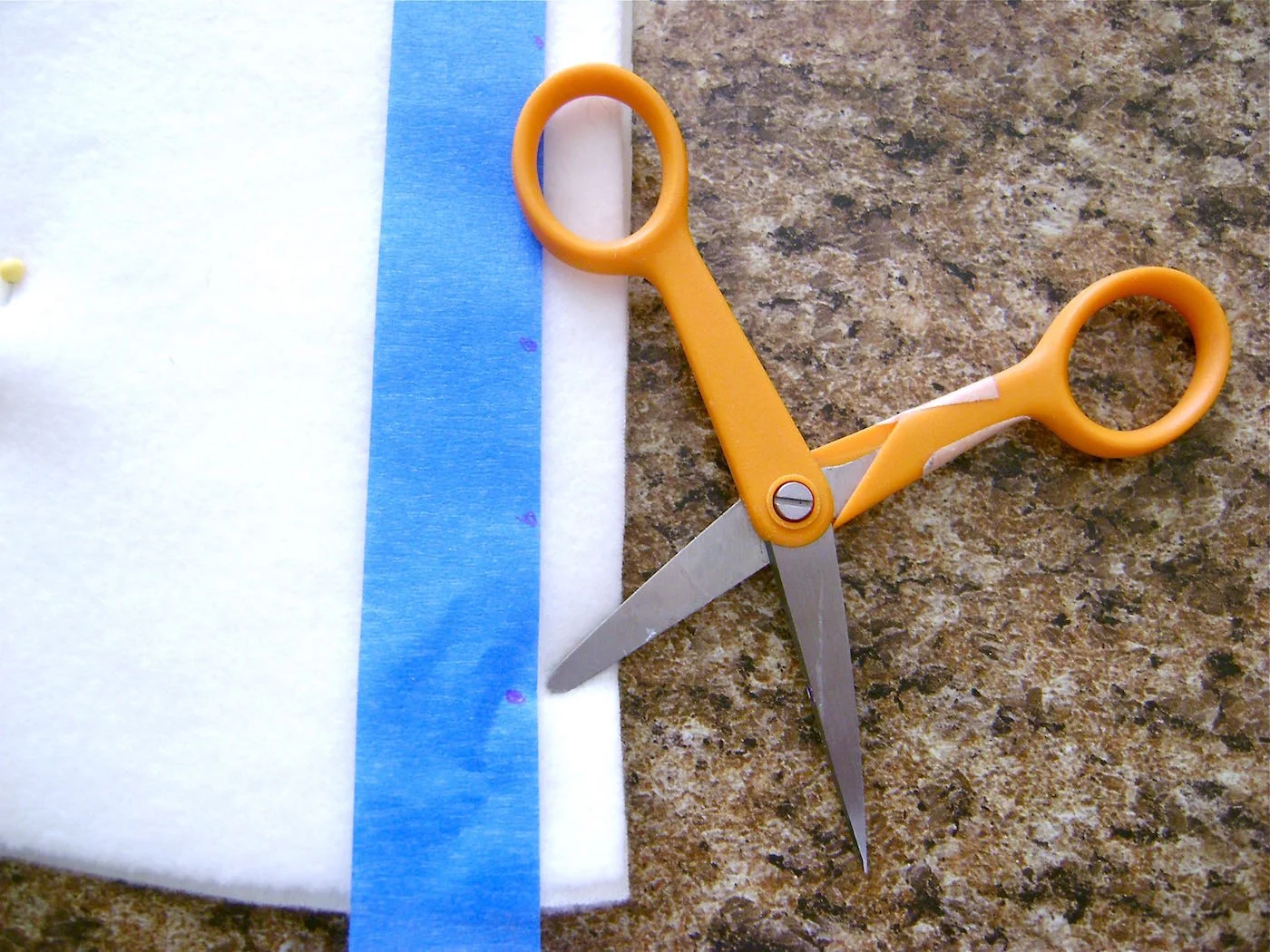 step 16 - With the sharp point of a very small scissor, poke holes in the fleece next to the one-inch marks. Pierce through both pieces. Remove the tape and save it to use again.