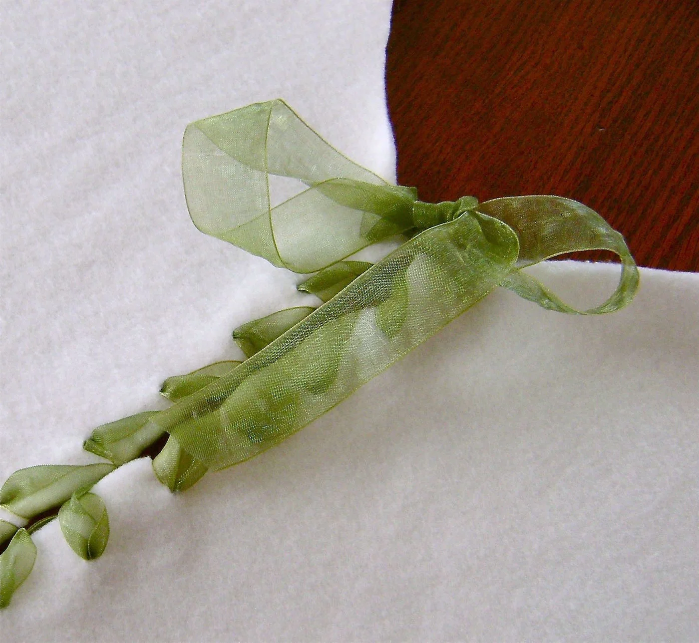 step 22 - Tie bows with the 6” tails to keep the skirt together after it is placed around the tree. Tuck all the bottom 3” tails into the bound and finished wraps on the underside of the skirt. 