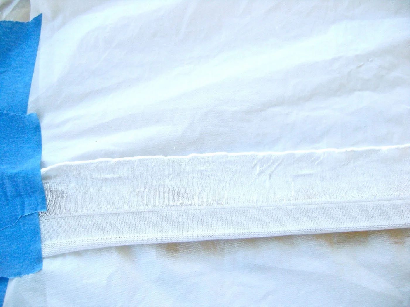 step 2 - To paint the ruffles, secure both ends of the strip to a covered work surface with painters tape. Work in sections if you don’t have the room to paint an entire strip at one time. The edges of the ruffle should be taught but not so tight it curls. 