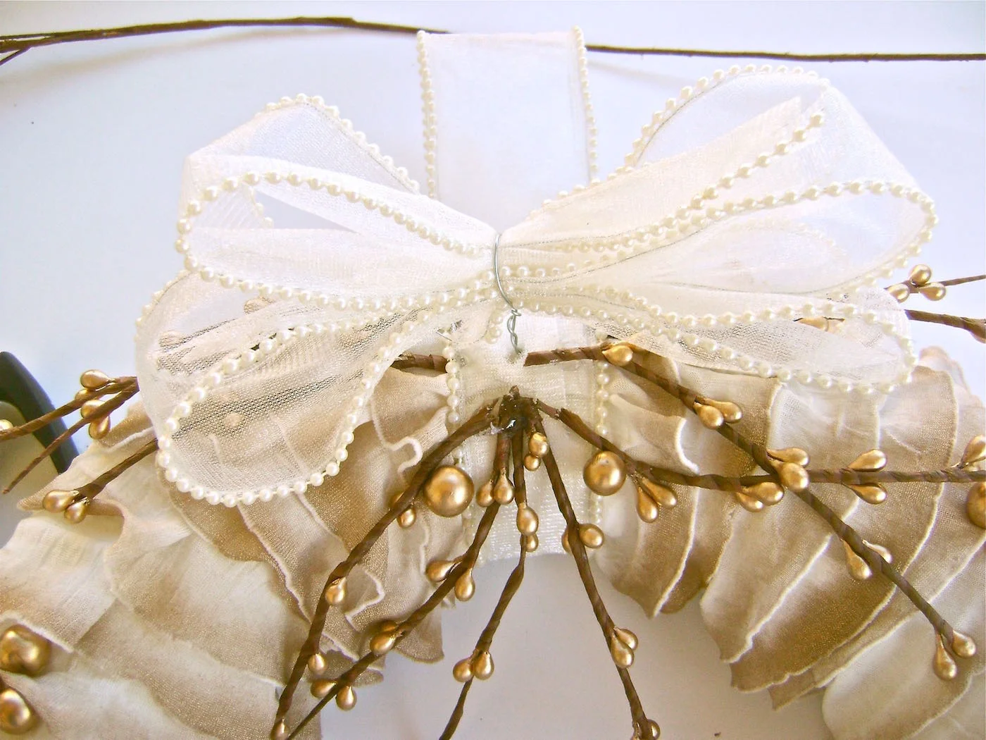 step 12 - Fill the hole with hot glue and push the bow’s wire ends inside. When the glue has set, use the ribbon tail to cover the wire. Glue in place. Add more stems below the bow.