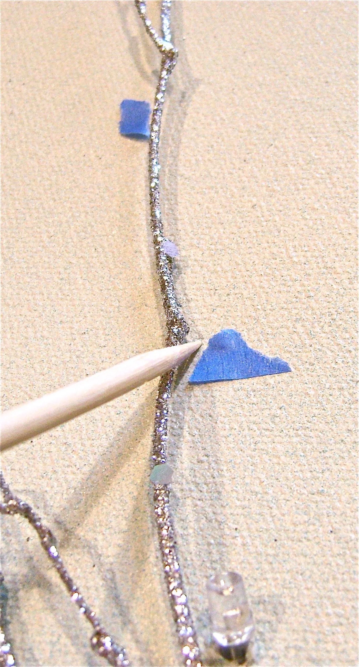 step 8 - One by one remove the pieces of tape replacing them with a hole. Use a sharp wood pick or other object to poke the hole. The object should be the size of the light or slightly smaller. After inserting the light, circle around it with hot glue to hold it in place.