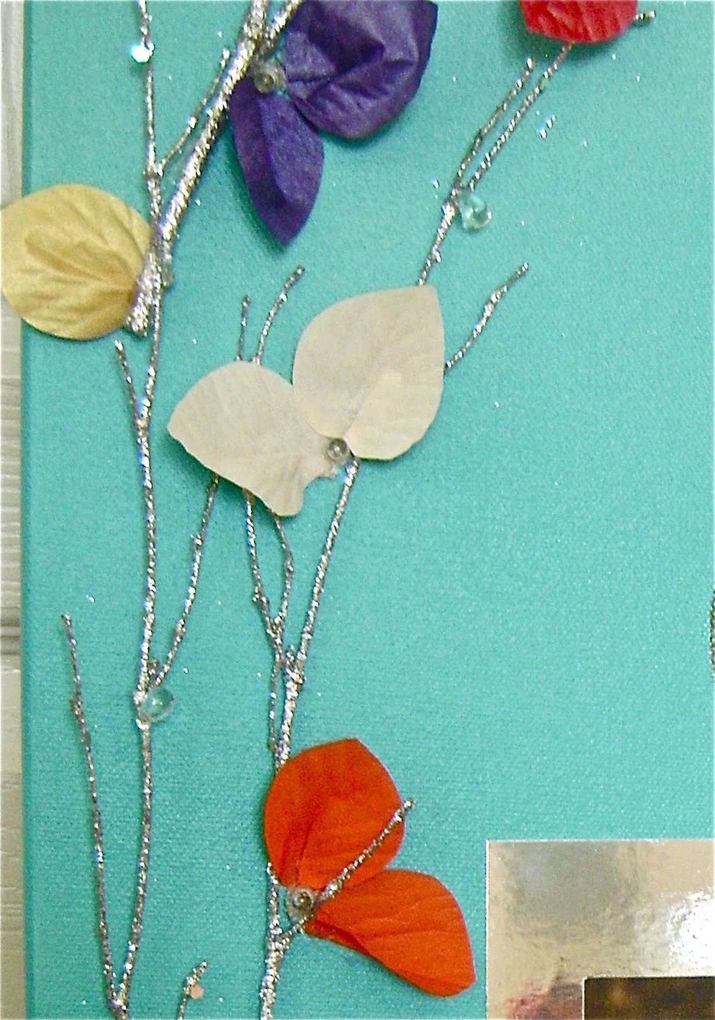 step 10 - I wasn’t happy with the very round petals so I trimmed them to create a different shape. Make a small pleat with your fingers in the center of the petals to make them curve. Glue one or two pleated petals onto the canvas around each light.
