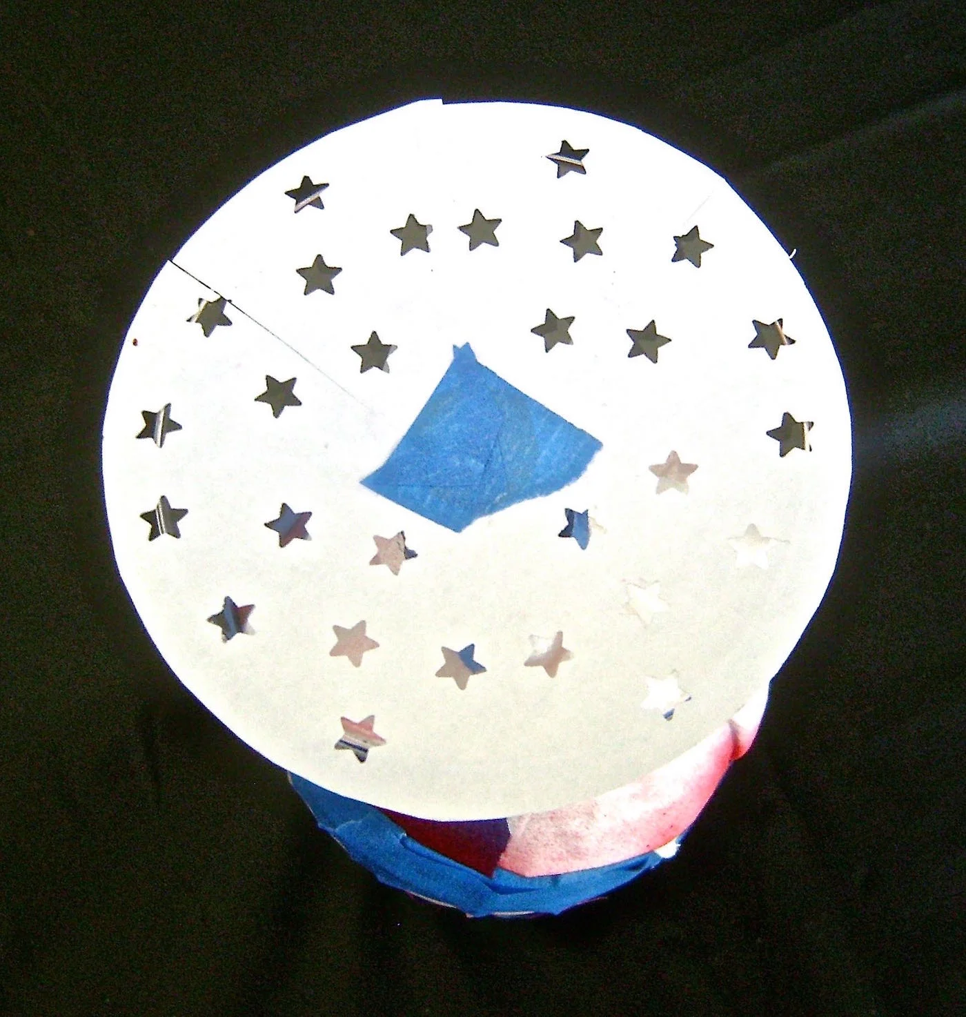 step 5 - Cut a piece of card stock in a circle slightly larger than the glass base. Fold the circle in fourths. Use a star paper punch to decorate the circle. Apply adhesive to one side of the circle and stick it to the glass base. Protect the rest of the glass from over spray.