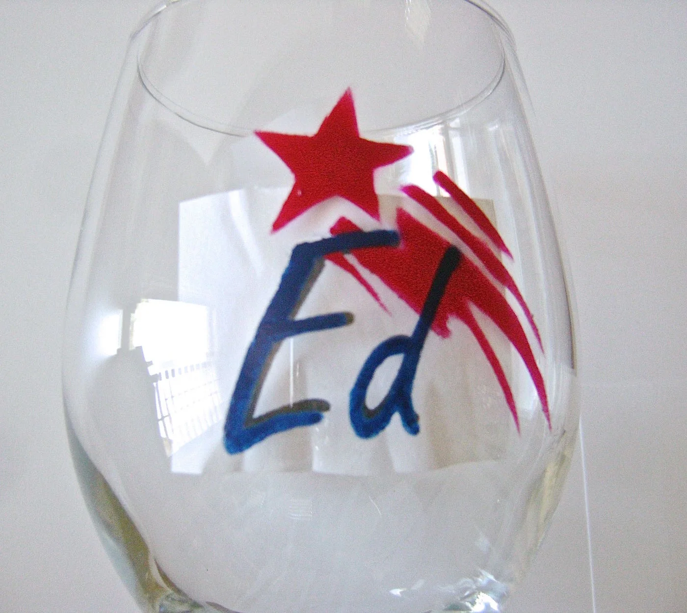 step 8 - Print out a name on copy paper. Choosing a font with thicker lines will make painting easier. Tape the printed card stock inside the glass. Trace the letters onto the glass using a fine brush and blue full-strength paint.
