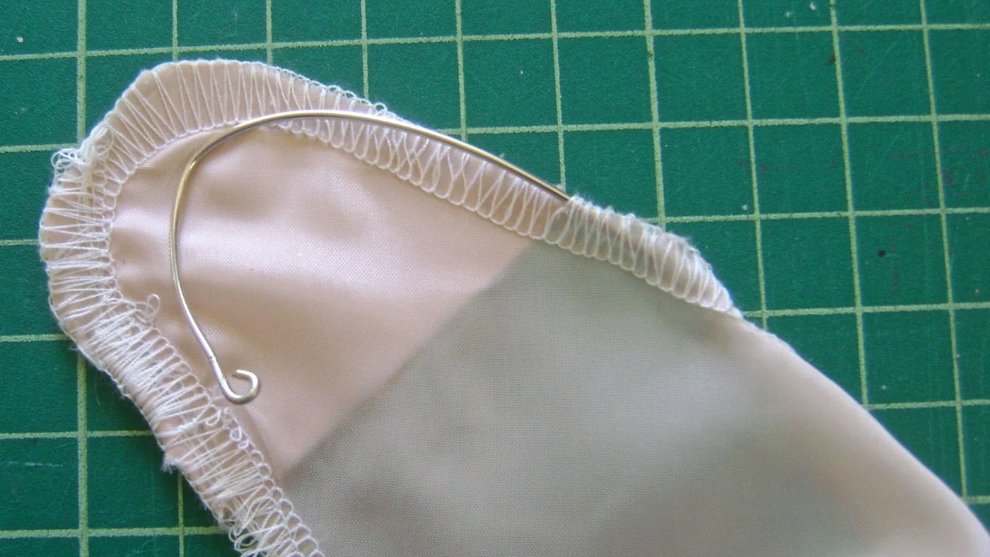 step 12 - The fabric should be taught on the wire in order to hang correctly. Curve the bottom few inches of the wire to match the original shape of the bottom facing. The facing was turned in step 5 to form an open pocket. Slip the curved wire into the pocket.