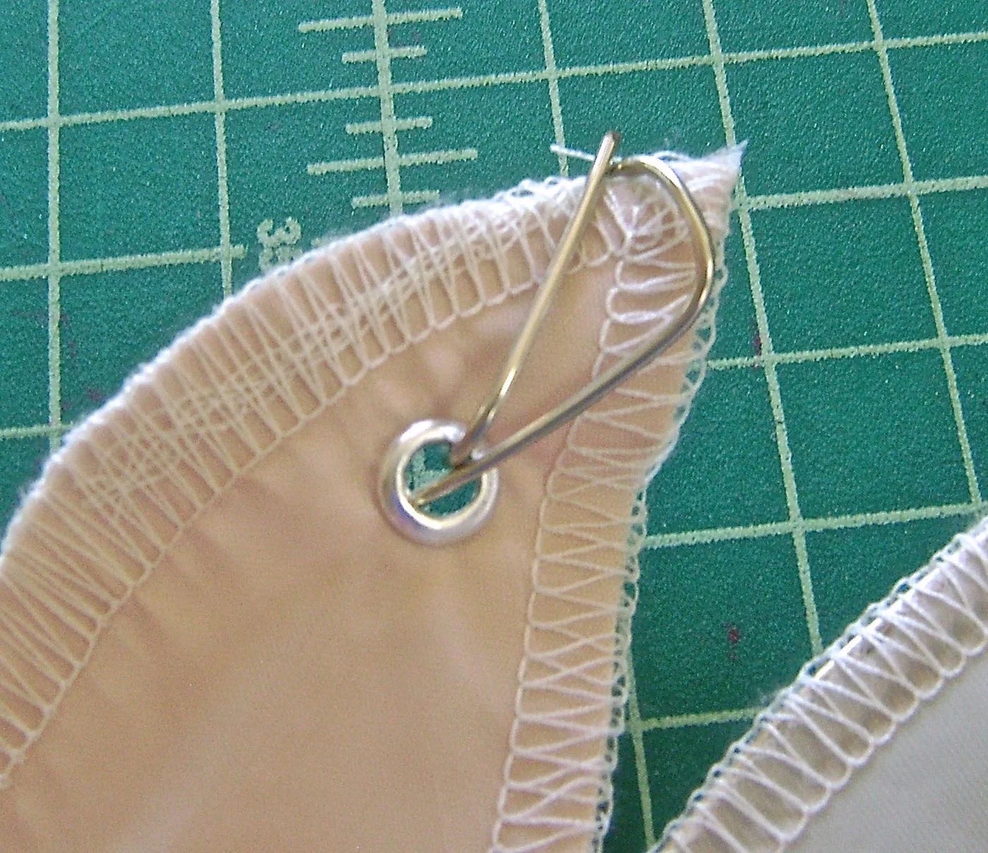 step 13 - Pull the fabric along the wire smoothly to the top facing. Bend the excess wire to slip it into the eyelet. Wrap it around and through the eyelet again. This will prevent the fabric from sliding down the wire. Prepare the second fabric panel in the same way.
