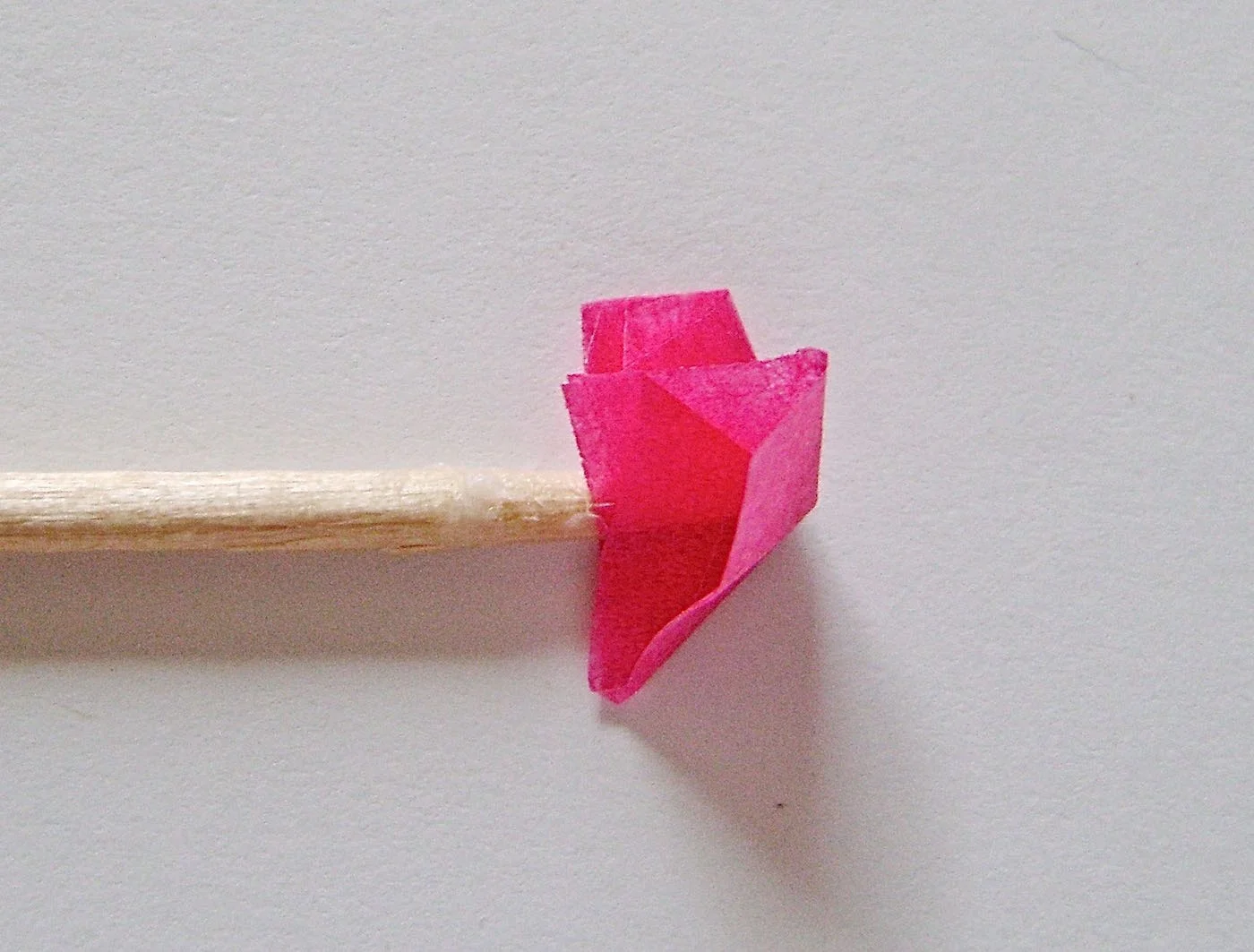step 7 - Place the tip of the toothpick into the center of a cut square. Bring all the corners up to the pick. Twist the tissue around the toothpick point then touch it onto the glue stick to pick up some glue. Press the point to a spot on the card to adhere the tissue then pull out the toothpick. Apply more flowers alternating with pink, orange and white. When the glue is set and the flowers are stuck to the card, use a toothpick to lift flattened edges and improve their shapes.