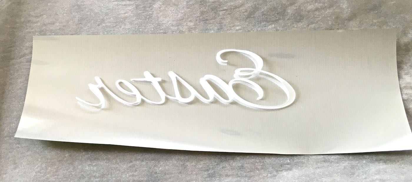 step 6 - Lay the adhesive side of the word on the non-shiny side of the foil. Place the two into parchment paper and iron.