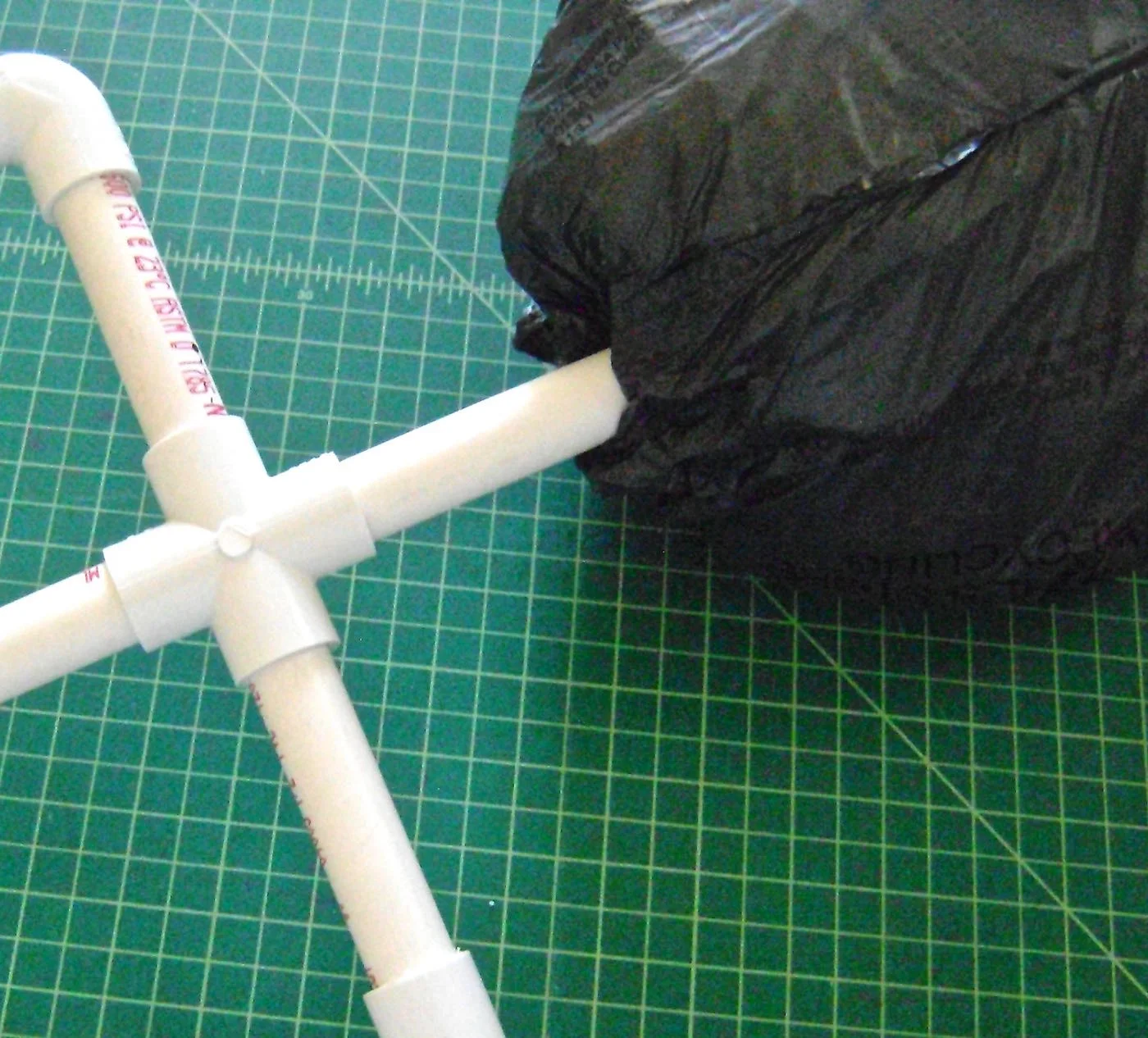 step 8 - Cut a small hole in the plastic and stuff the neck all the way into the head. Apply hot glue to the base to secure the plastic to the pipe.