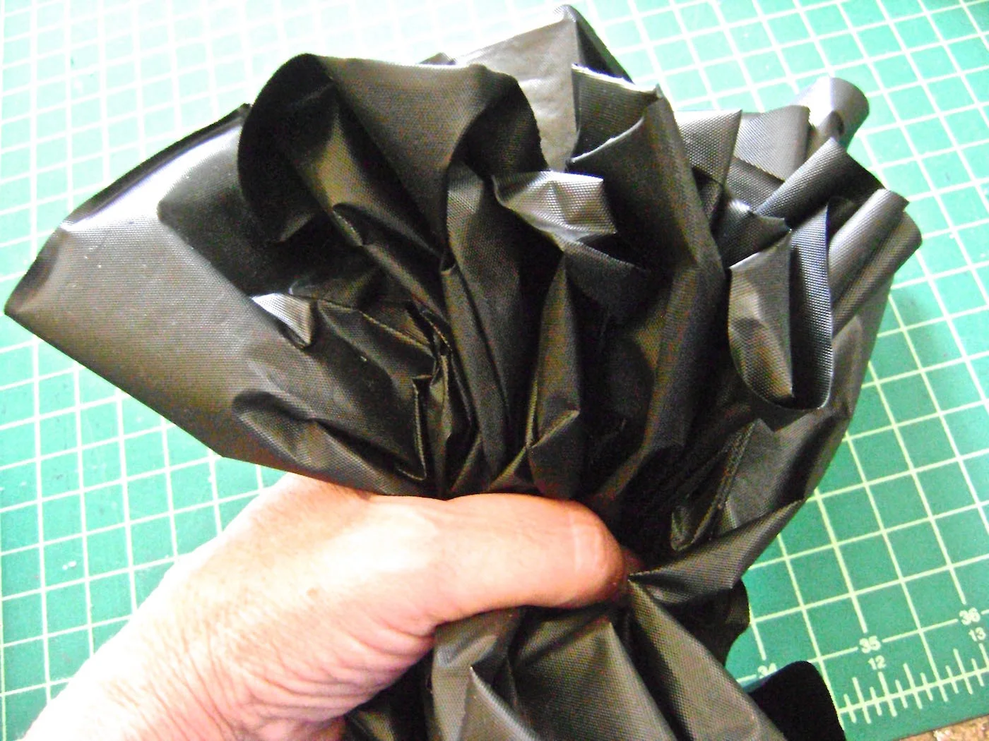 step 10- Open the third plastic table cover. Cut it in half. Gather it together in your hand and use a plastic strip to tie it to the front neck. Before securing it, distribute the material so that it is not all clumped in the front. It should reach the sides of the witch. Attach the second half of this table cover to the back of the witch in the same manner. Optional : Cut a few long slices into the plastic covering the body frame to move in the breeze. Fringe the gathered pieces around the neck to add interest. 