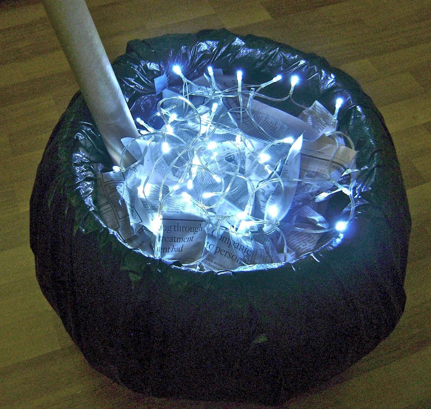step 14 - Fill the cauldron with crumpled newspaper almost to the top of the container. Scatter the lights about. 