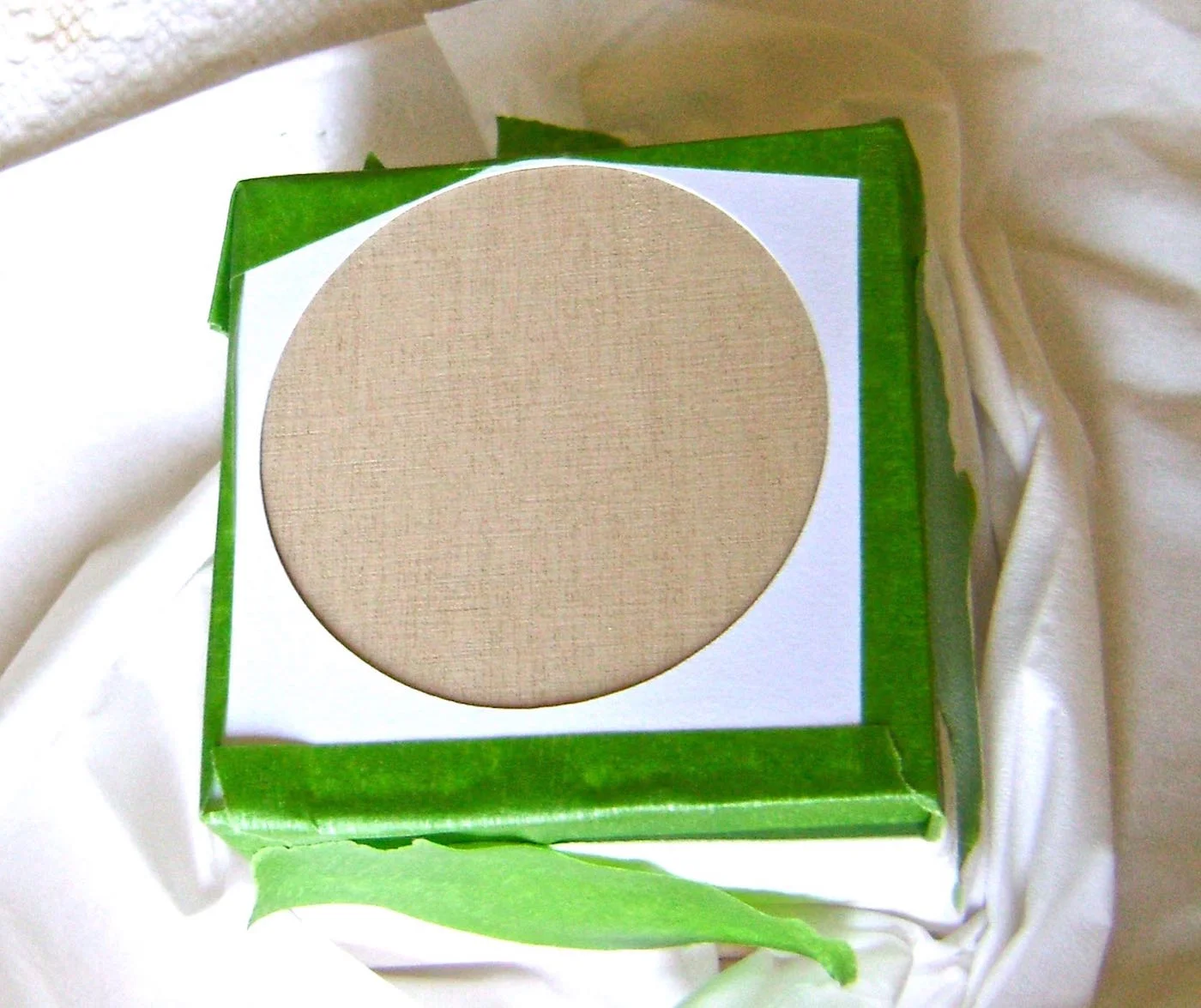 step 4 - Spray the back of the circle stencil with adhesive and press it to the cube. Mask off the rest of the cube and spray the stencil with yellow paint.