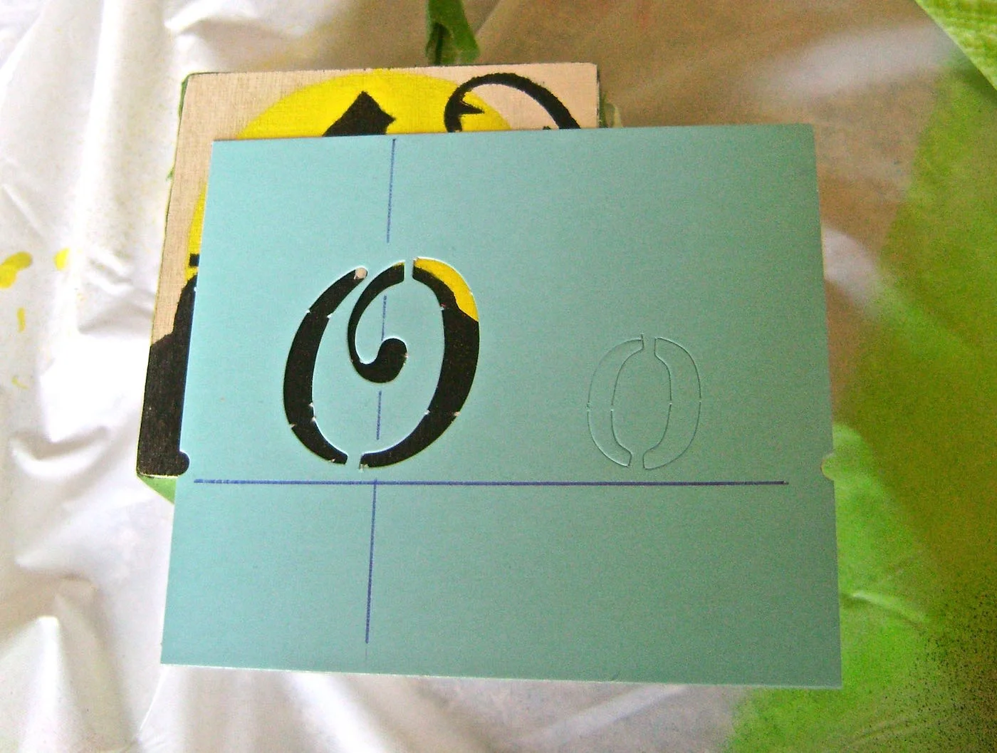 step 7 - Center the letter stencil over the design and close to the bottom of the cube. Mask off the rest of the design and airbrush the letter with orange paint.