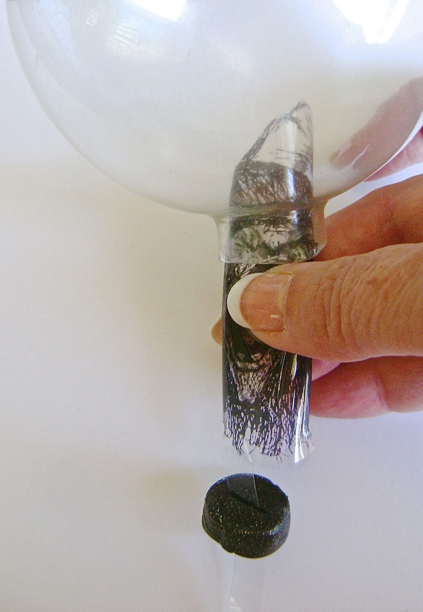 step 5 - Vertically roll up the image so that it fits inside the ornament opening. Insert it. The plastic will pop open and stand up inside. Pull the stem down and push the plug up until it is seated in the opening. 